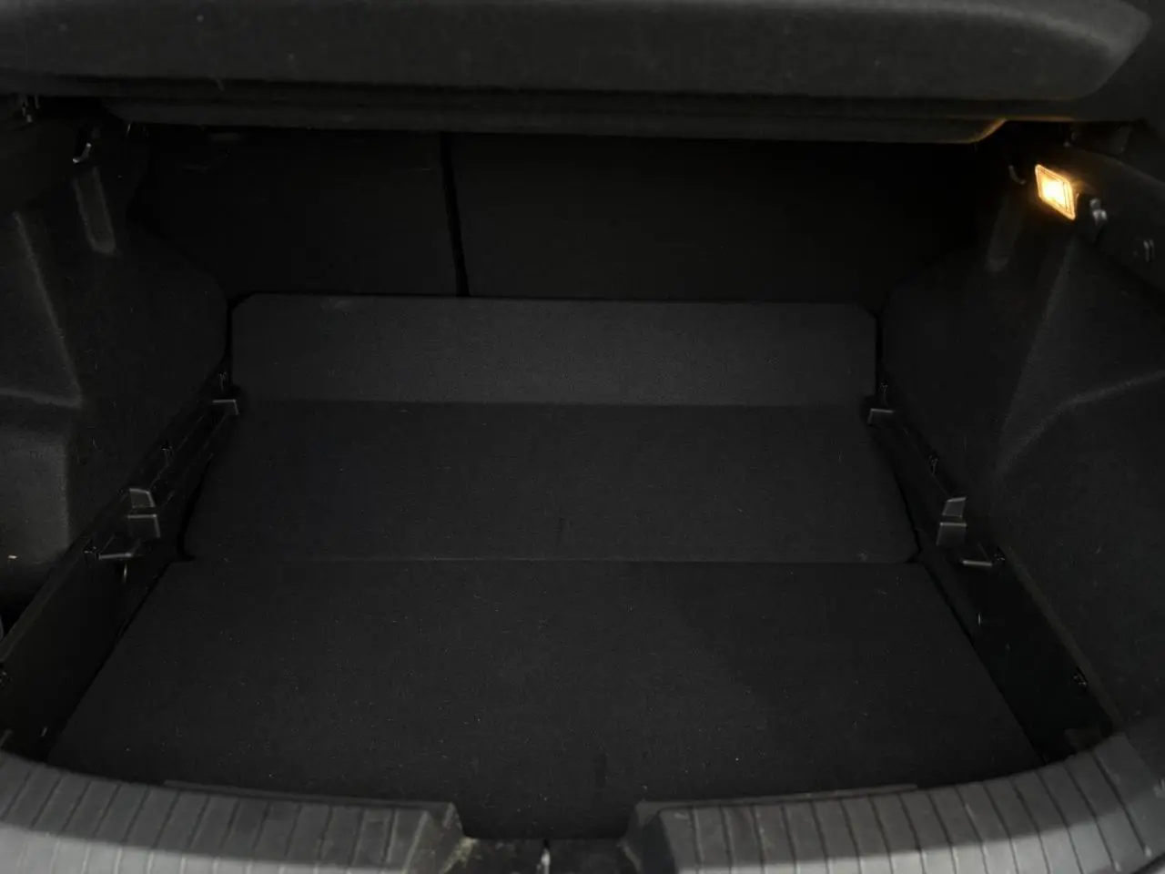 Coffre vide vu de face du Dacia Duster 2024 beige Sandstone avec éclairage intérieur allumé.