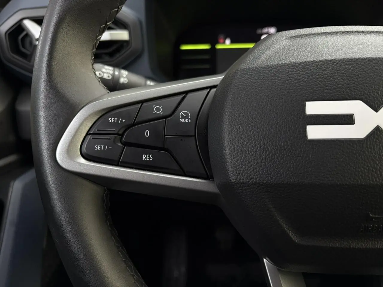 Gros plan sur les commandes au volant à gauche du Dacia Duster 2024 beige Sandstone, version ECO-G 100 Journey.