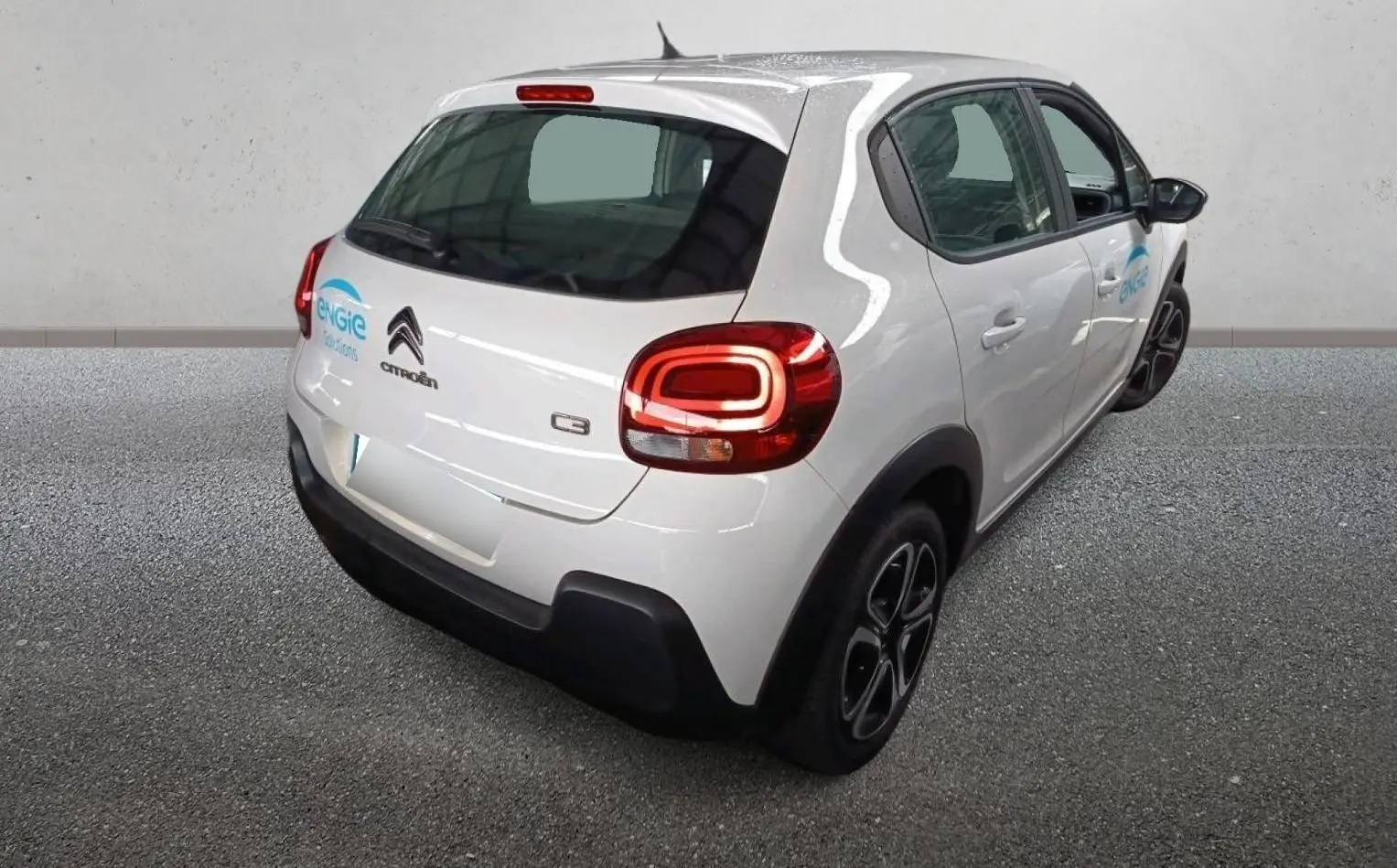Vue 3/4 arrière droite d'une Citroën C3 Société blanche avec logo Engie sur porte arrière, feux arrière allumés.