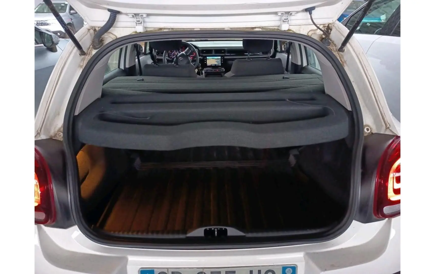 Vue arrière ouverte du coffre d'une Citroën C3 Société blanche, montrant l'intérieur et la planche cache-bagages.