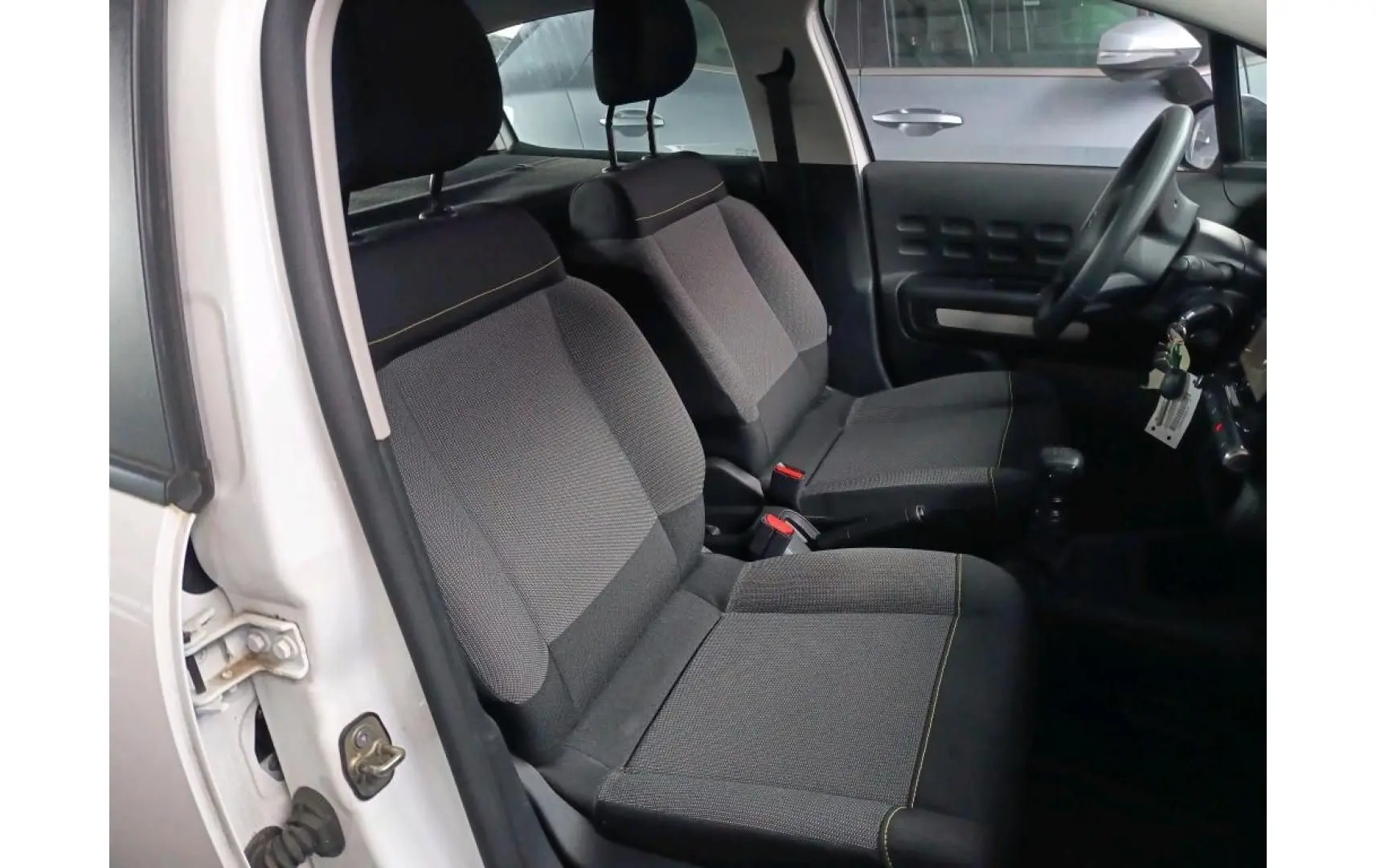 Vue intérieure côté gauche montrant les sièges avant gris et noirs d'une Citroën C3 Société blanche de 2021.