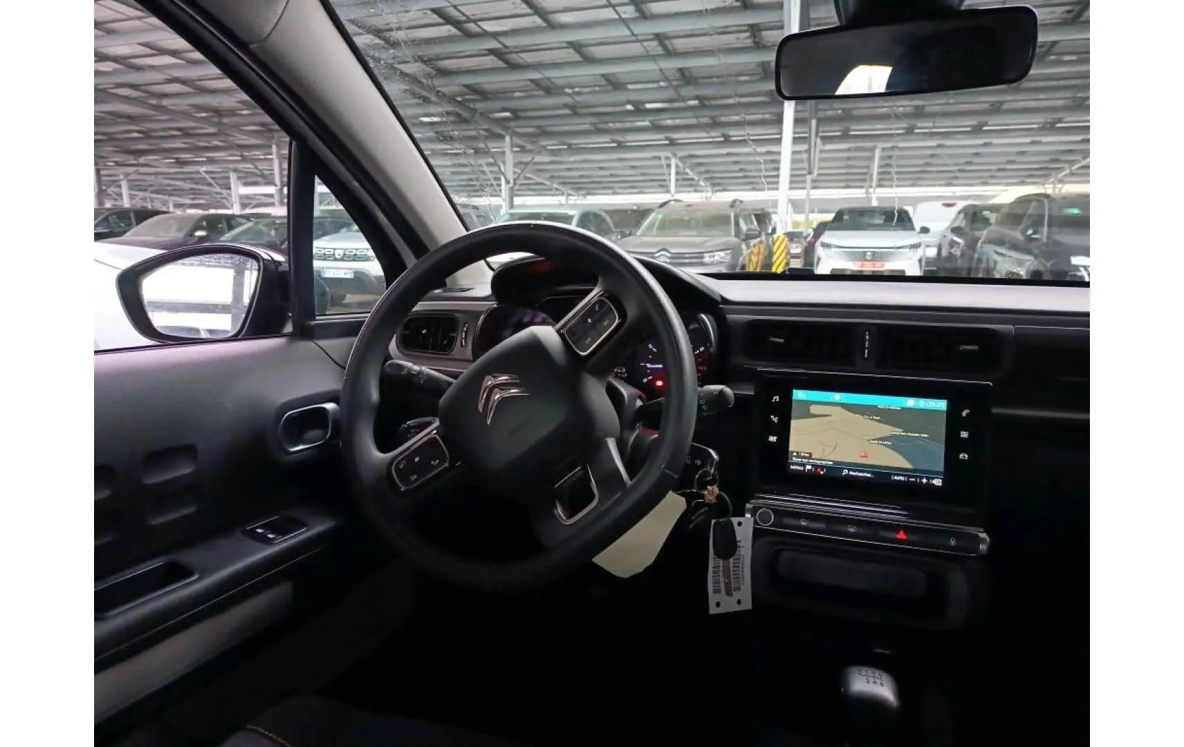 Vue intérieure côté conducteur de la Citroën C3 Société 2021 avec tableau de bord noir et écran tactile GPS allumé.