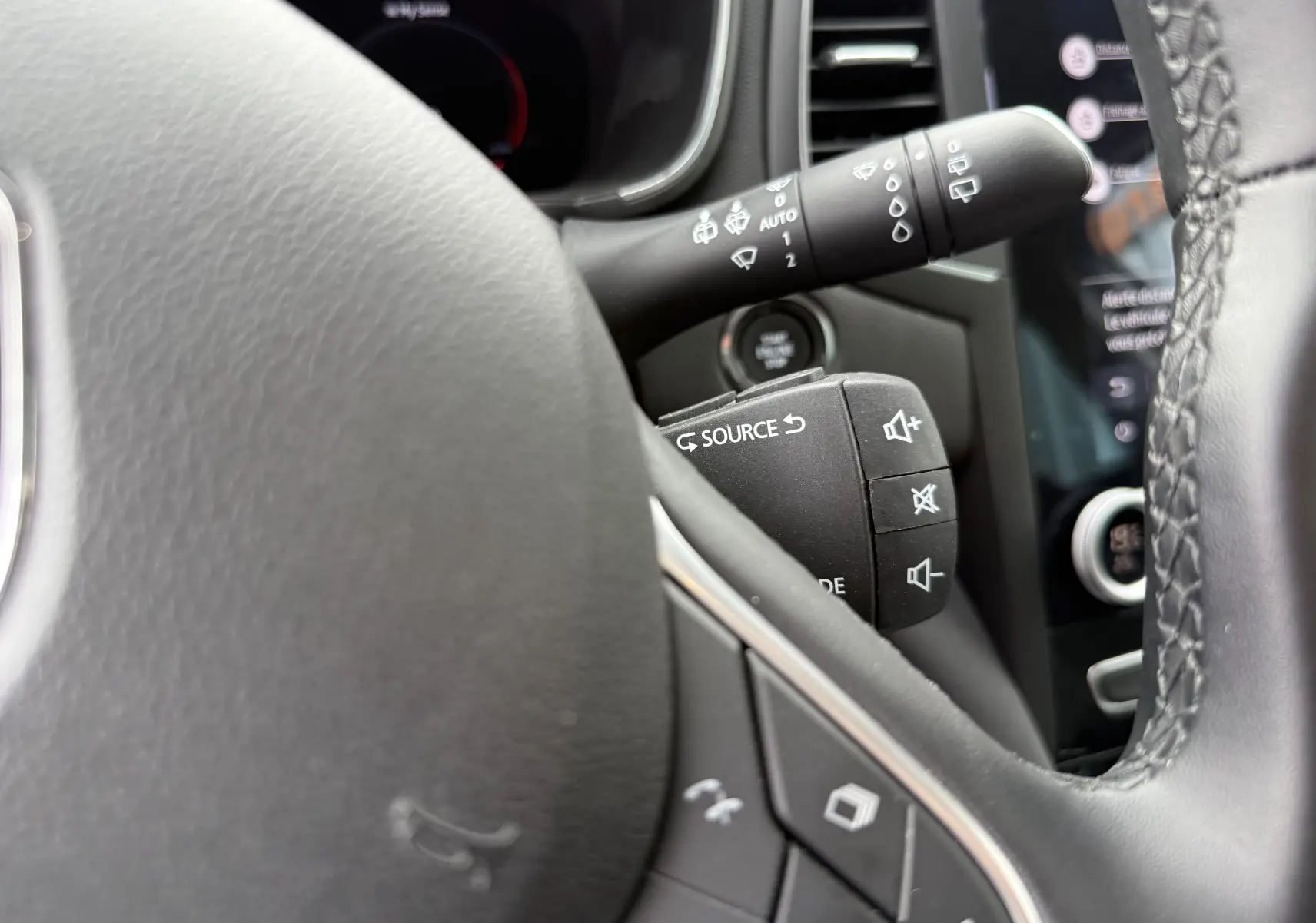 Gros plan sur les commandes au volant en cuir noir de la Renault Mégane Break 2024 gris Highland Metal.