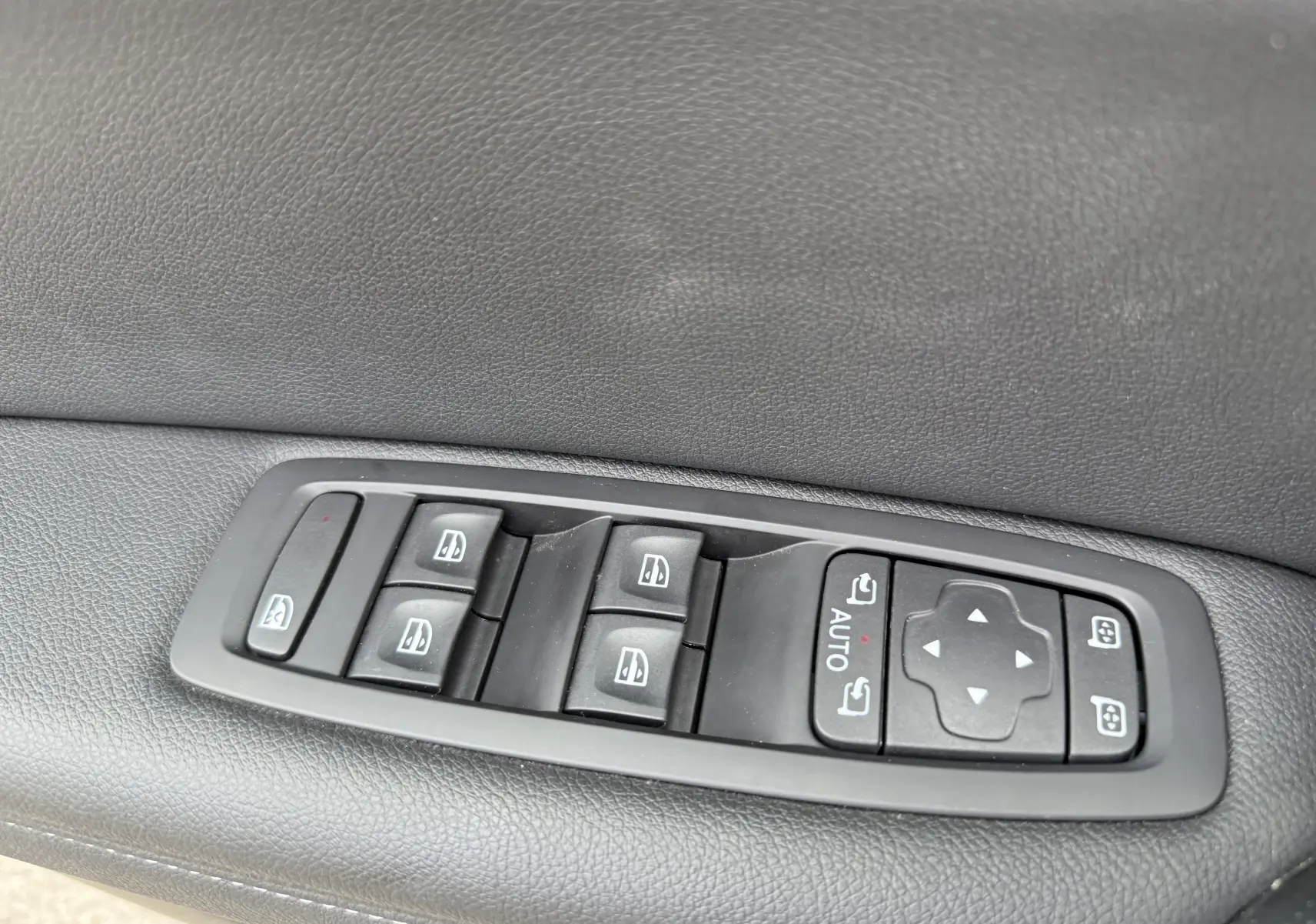 Panneau de commandes des vitres électriques et réglage des rétroviseurs sur la porte côté gauche d’une Renault Mégane Break gris Highland Metal 2024.