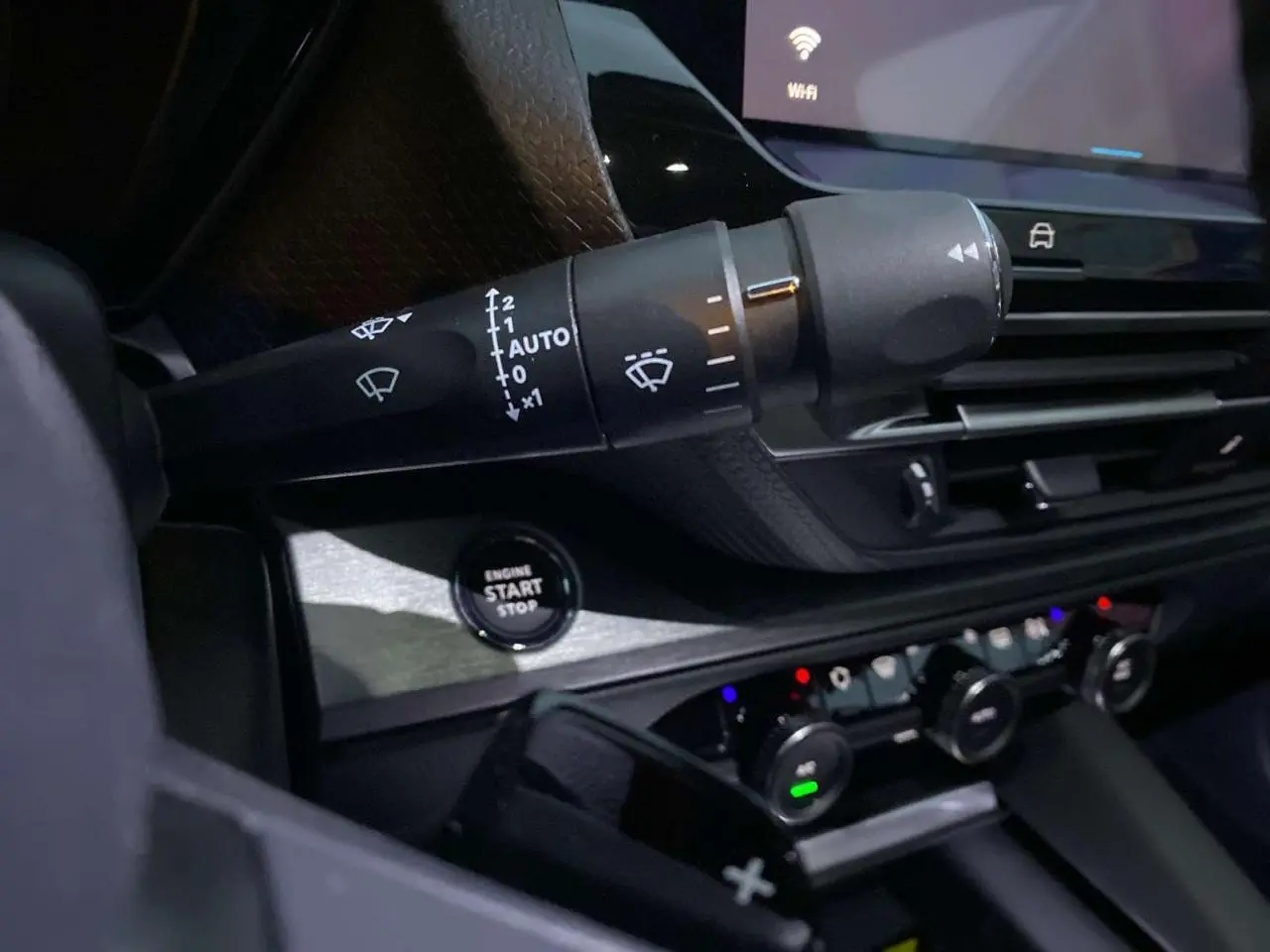 Gros plan sur la commande d'essuie-glace et le bouton start/stop dans l'habitacle sombre d'une Citroën C5 X 2023.