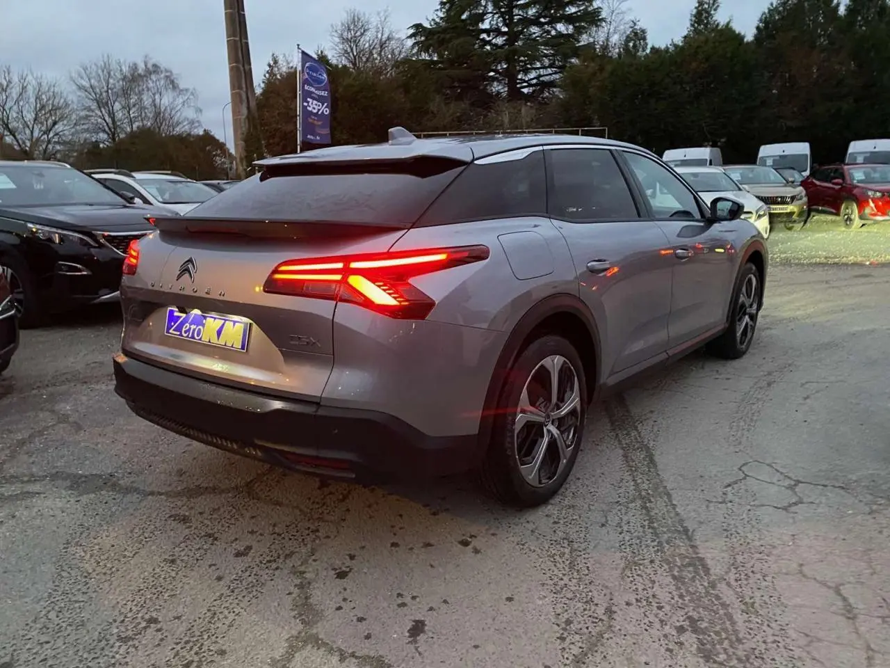 Vue 3/4 arrière droite d'une Citroën C5 X gris Artense métallisé avec feux arrière LED distinctifs allumés.