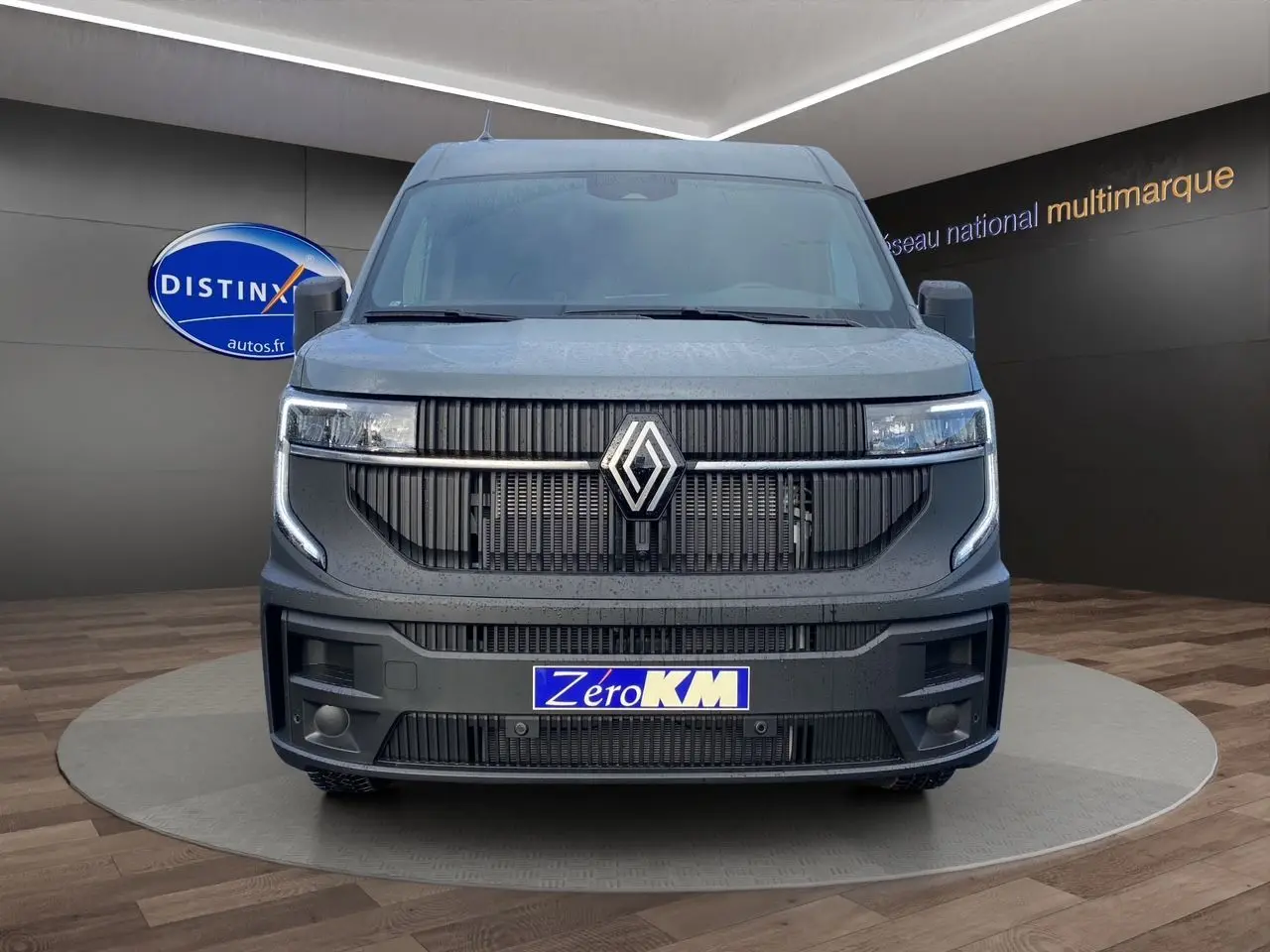 Vue frontale du Renault Master gris urbain 2025 avec calandre noire et plaque d'immatriculation "Zéro KM" visible.