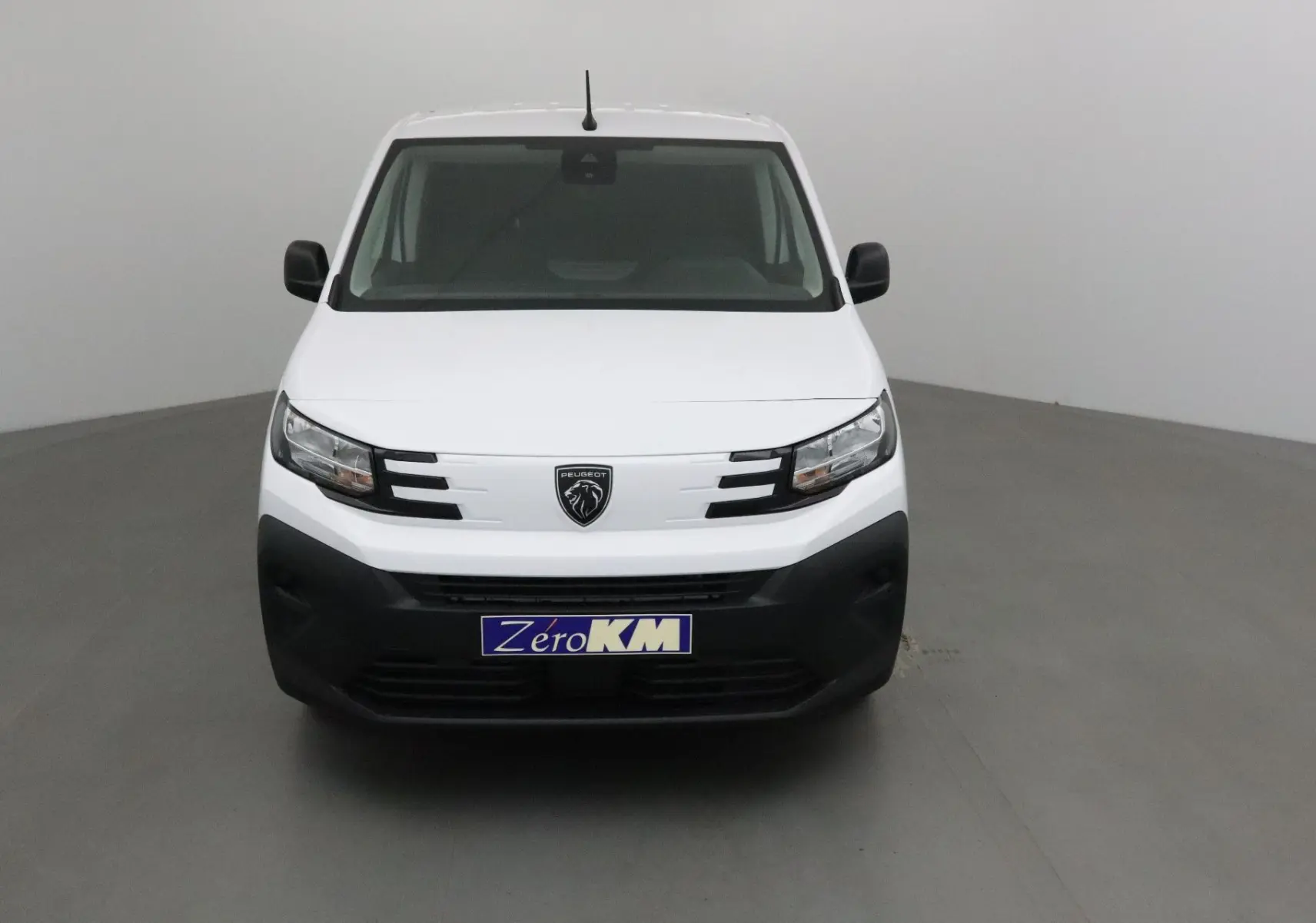 Vue frontale d’un utilitaire Peugeot Partner blanc 2025 avec calandre noire et logo lion central.