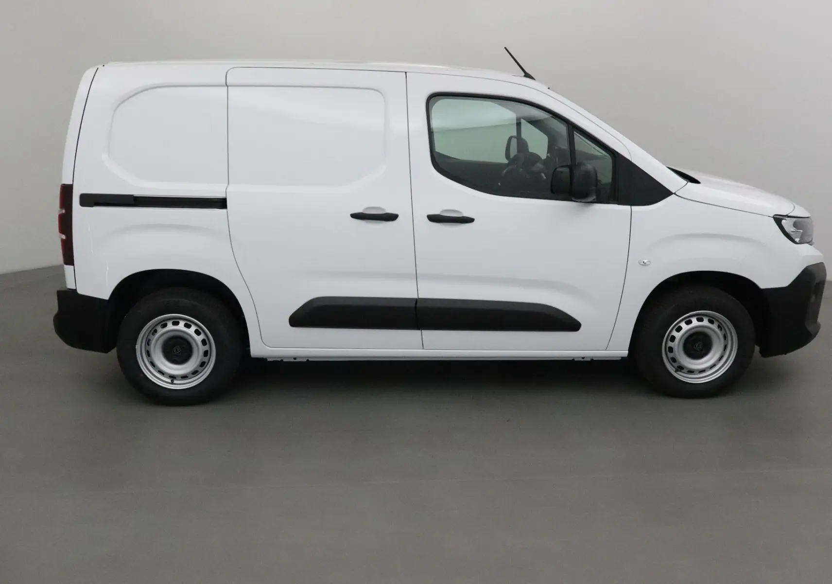 Peugeot Partner blanc vu de profil côté droit, fourgonnette utilitaire avec protections noires sur les portières.