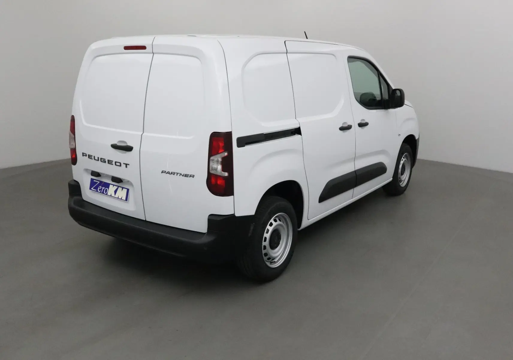 Vue 3/4 arrière droite d’un utilitaire Peugeot Partner blanc, portes arrière battantes et bandeau noir latéral.