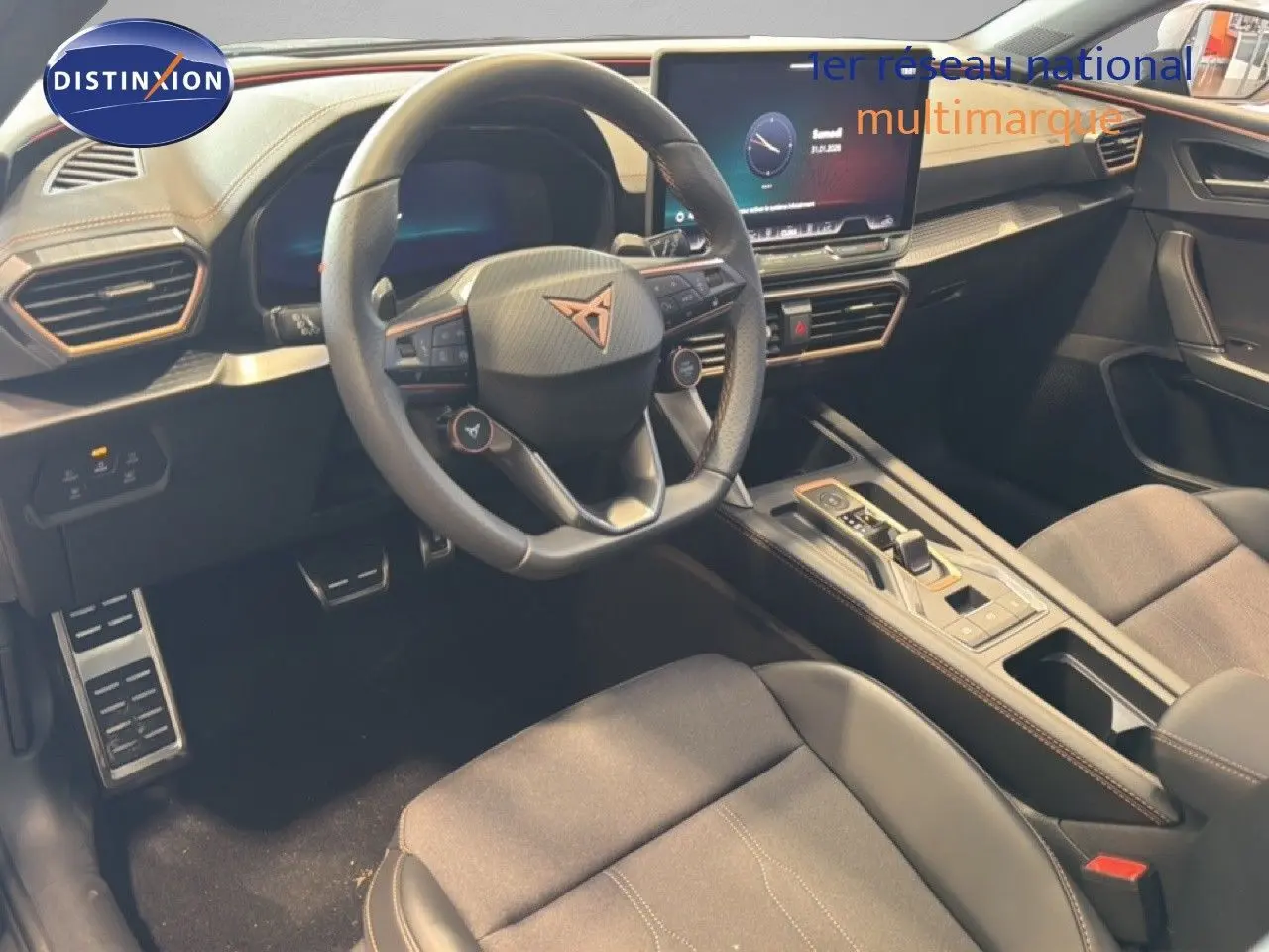 Vue intérieure de face du poste de conduite de la CUPRA LEON ST 1.5 eTSI avec volant multifonction et écran tactile.