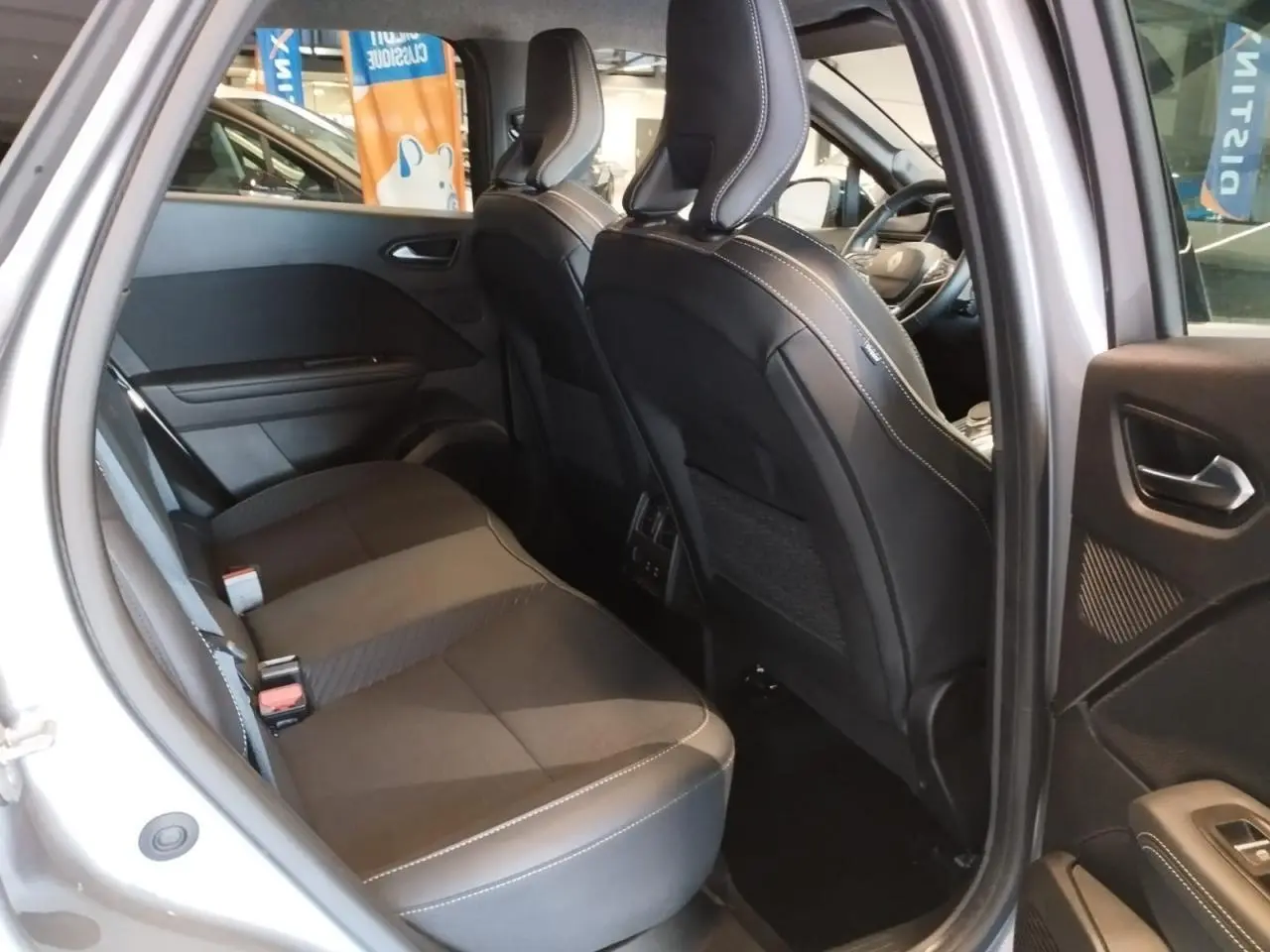 Vue intérieure côté droit sur la banquette arrière et les sièges avant en cuir noir du Renault Symbioz gris Cassiopée 2025.
