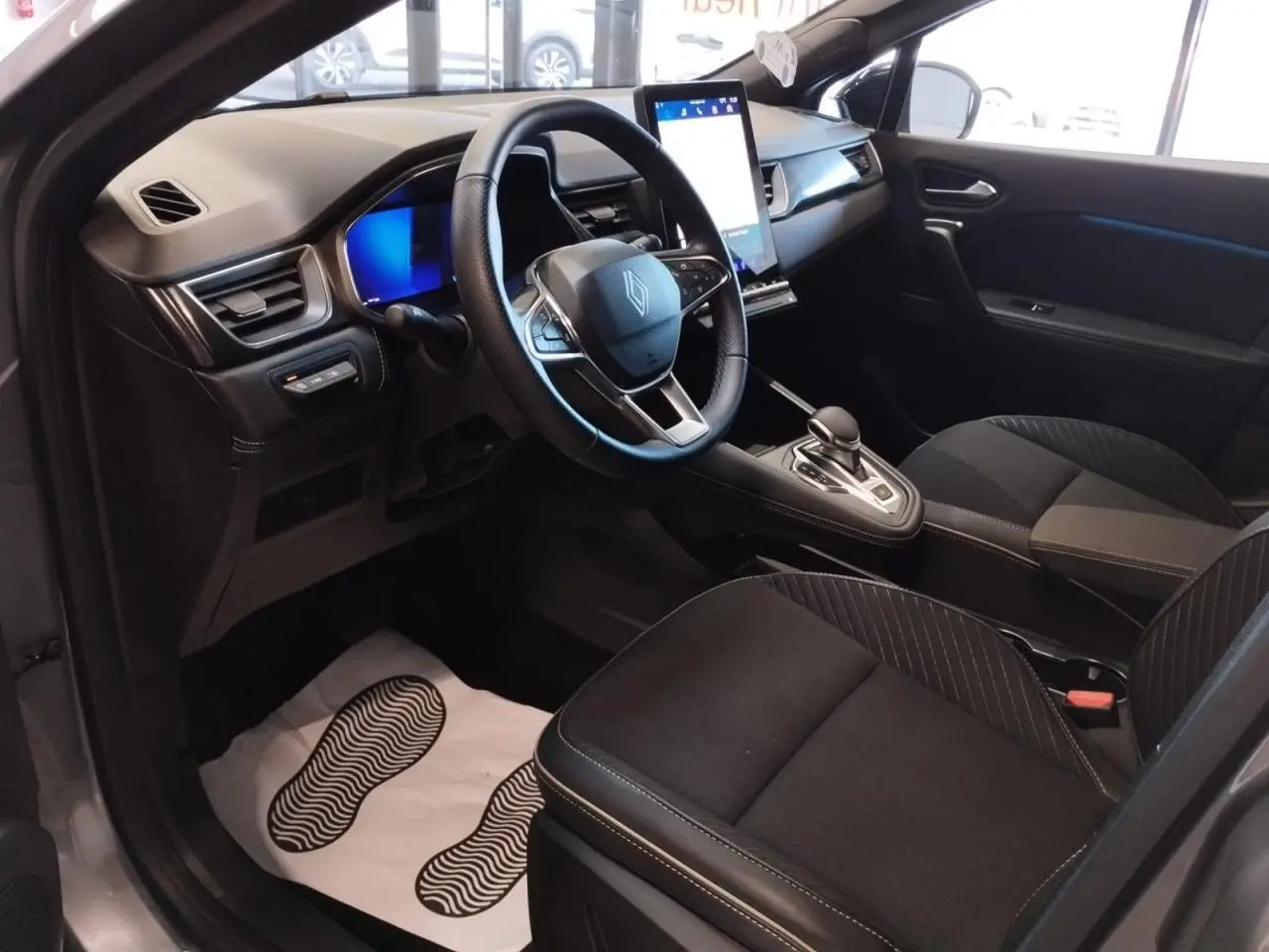 Vue intérieure côté conducteur du Renault SYMBIOZ gris Cassiopée, avec tableau de bord numérique et écran tactile vertical.