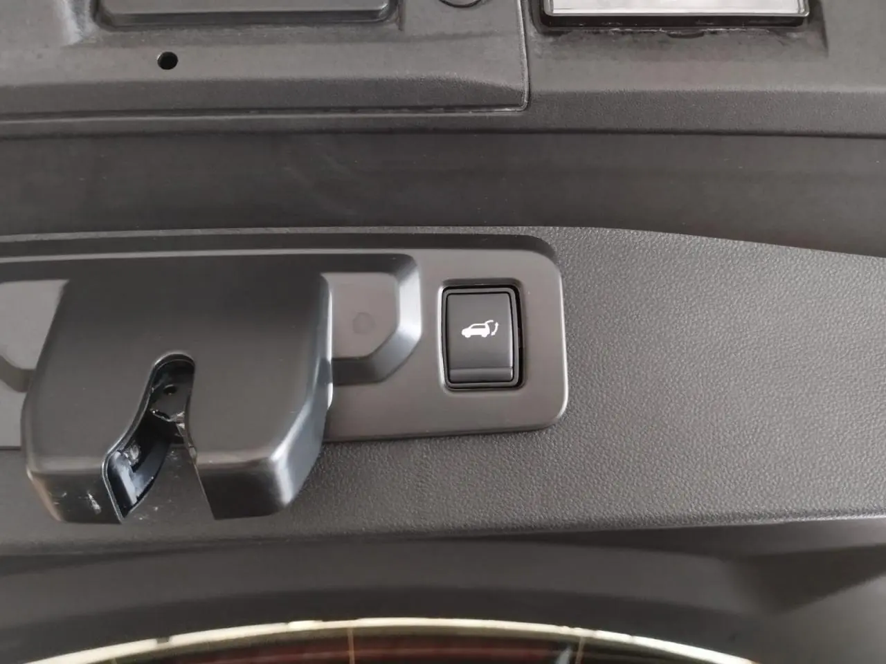 Gros plan sur le bouton d'ouverture du hayon motorisé dans le coffre du Renault SYMBIOZ gris Cassiopée.