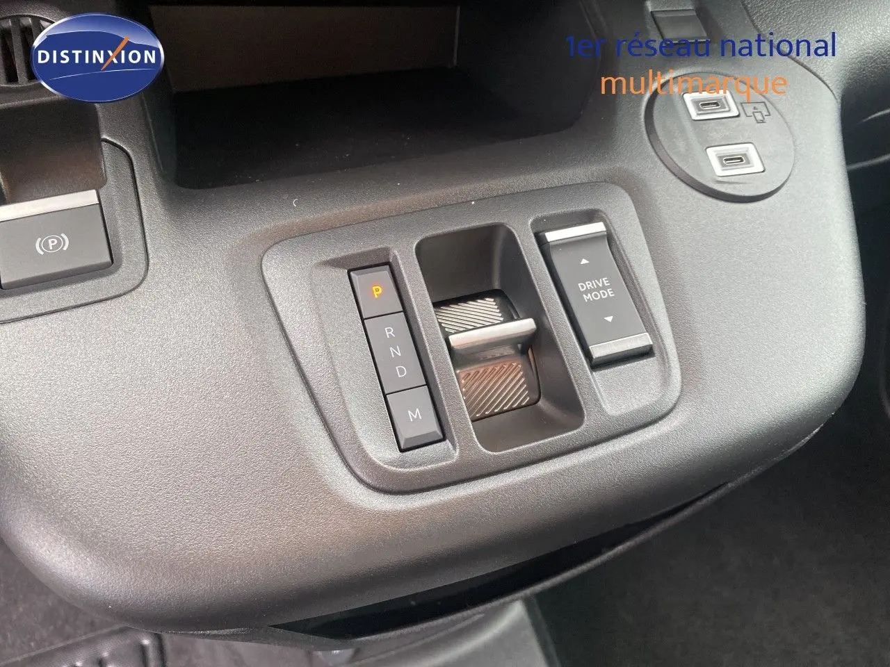 Gros plan sur la console centrale grise du Citroën Berlingo Fourgon blanc, montrant la commande de boîte auto et le bouton Drive Mode.
