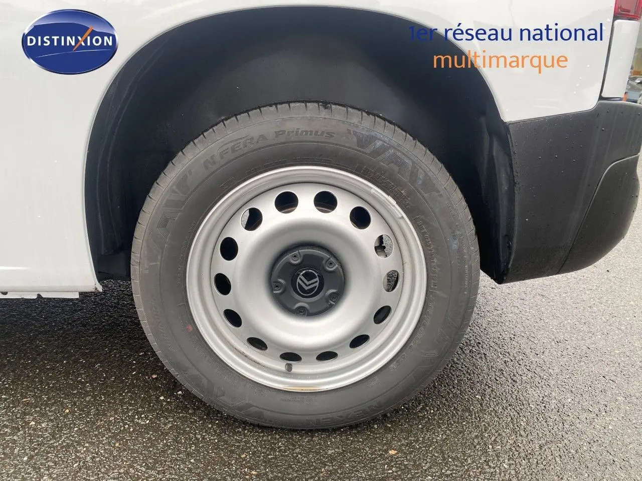 Gros plan sur la roue avant droite en jante acier du Citroën Berlingo Fourgon blanc, avec partie basse de la carrosserie visible.