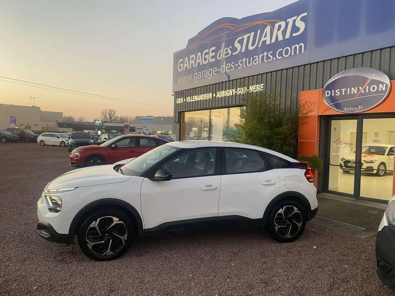 Citroën C4 blanc vue de profil côté gauche, garée devant un garage avec jantes noires et toit noir contrastant.