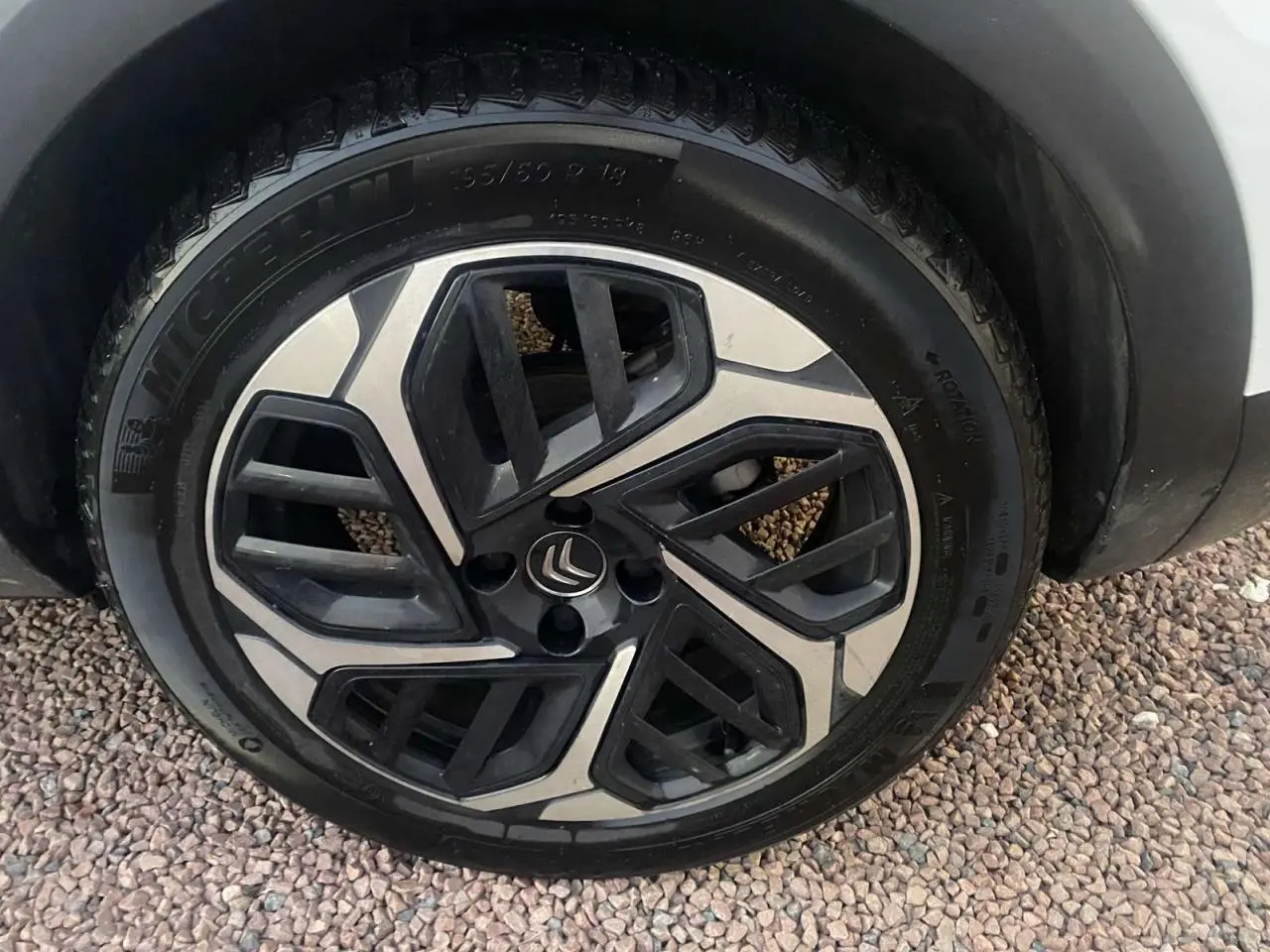 Gros plan sur la roue avant droite d'une Citroën C4 blanche de 2021, avec jante alliage au design moderne.