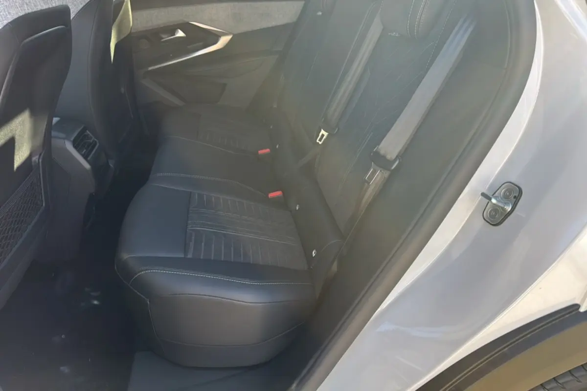 Vue intérieure côté arrière droit du Peugeot 3008 Hybrid 136 GT Plus blanc okénite, sièges en cuir noir avec surpiqûres.