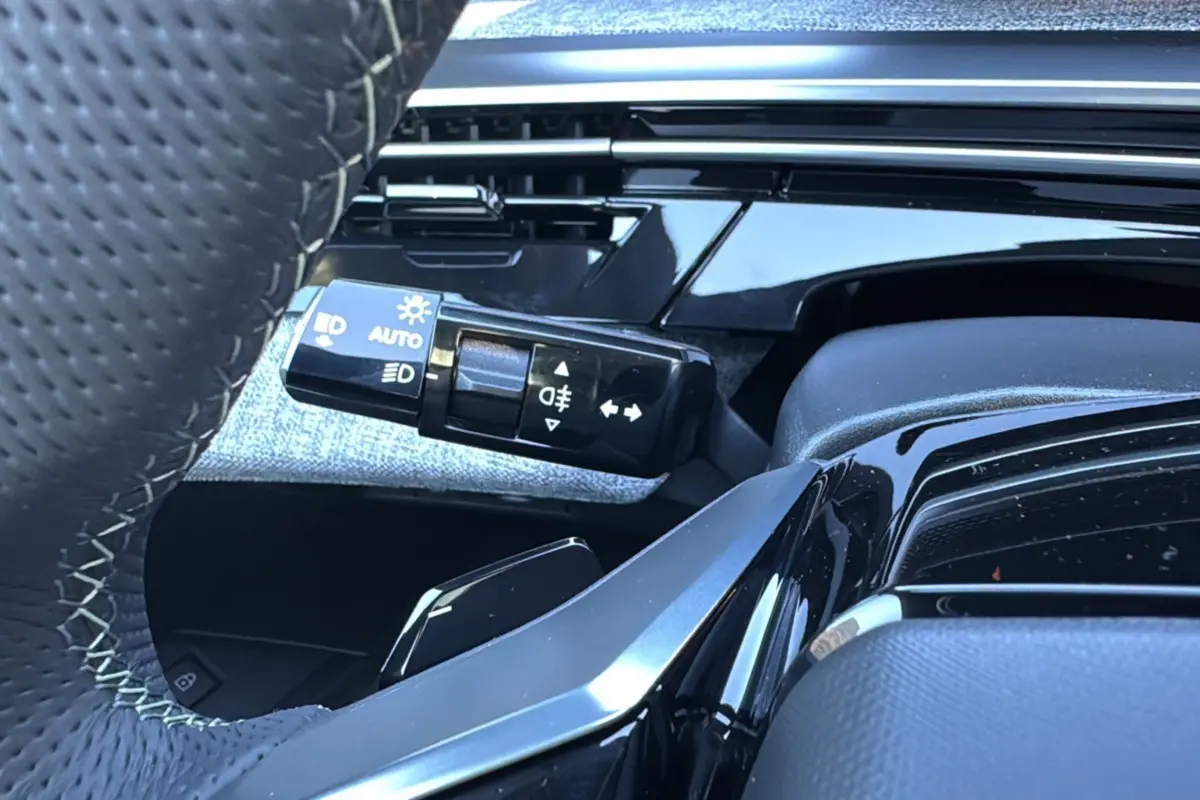 Gros plan sur la manette de commandes des phares et clignotants à gauche du volant du Peugeot 3008 Hybrid blanc okénite 2024.