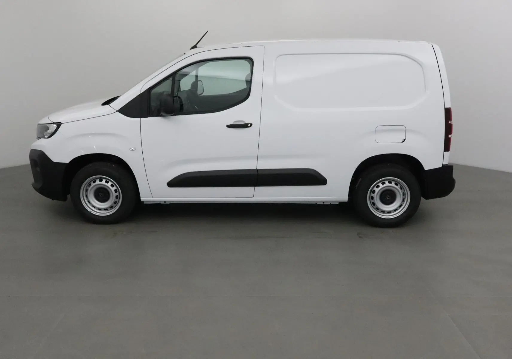 Vue de profil côté gauche d’un Peugeot Partner blanc 2025, fourgon compact avec protections noires sur les portières.