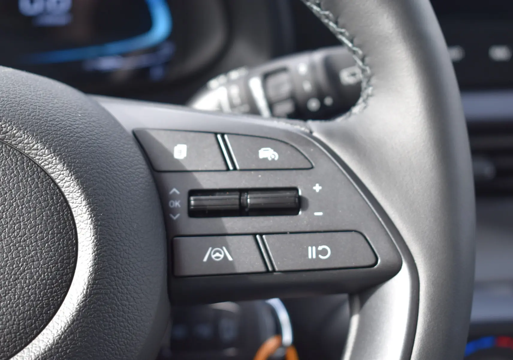 Gros plan sur les commandes multifonctions du volant en cuir noir de la Hyundai i20 1.2 79 Intuitive 2025.