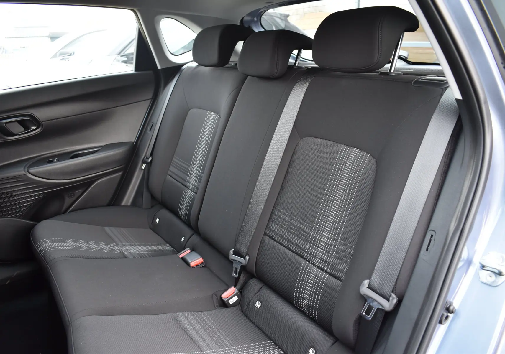 Vue intérieure côté droit montrant la banquette arrière noire avec motifs gris d'une Hyundai i20 bleu clair 2025.