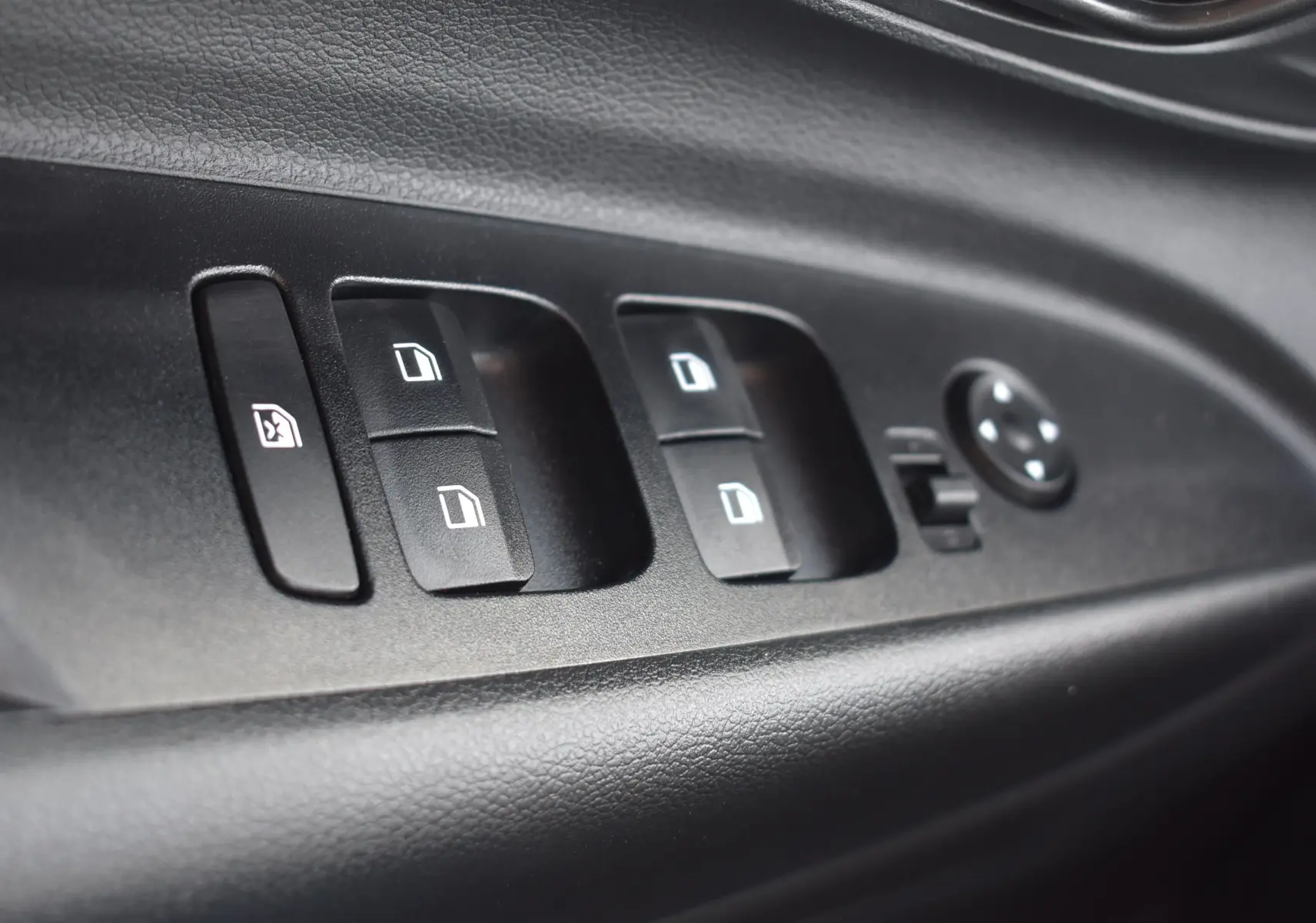 Gros plan sur les commandes de lève-vitres et réglage des rétroviseurs côté conducteur d’une Hyundai i20 2025.