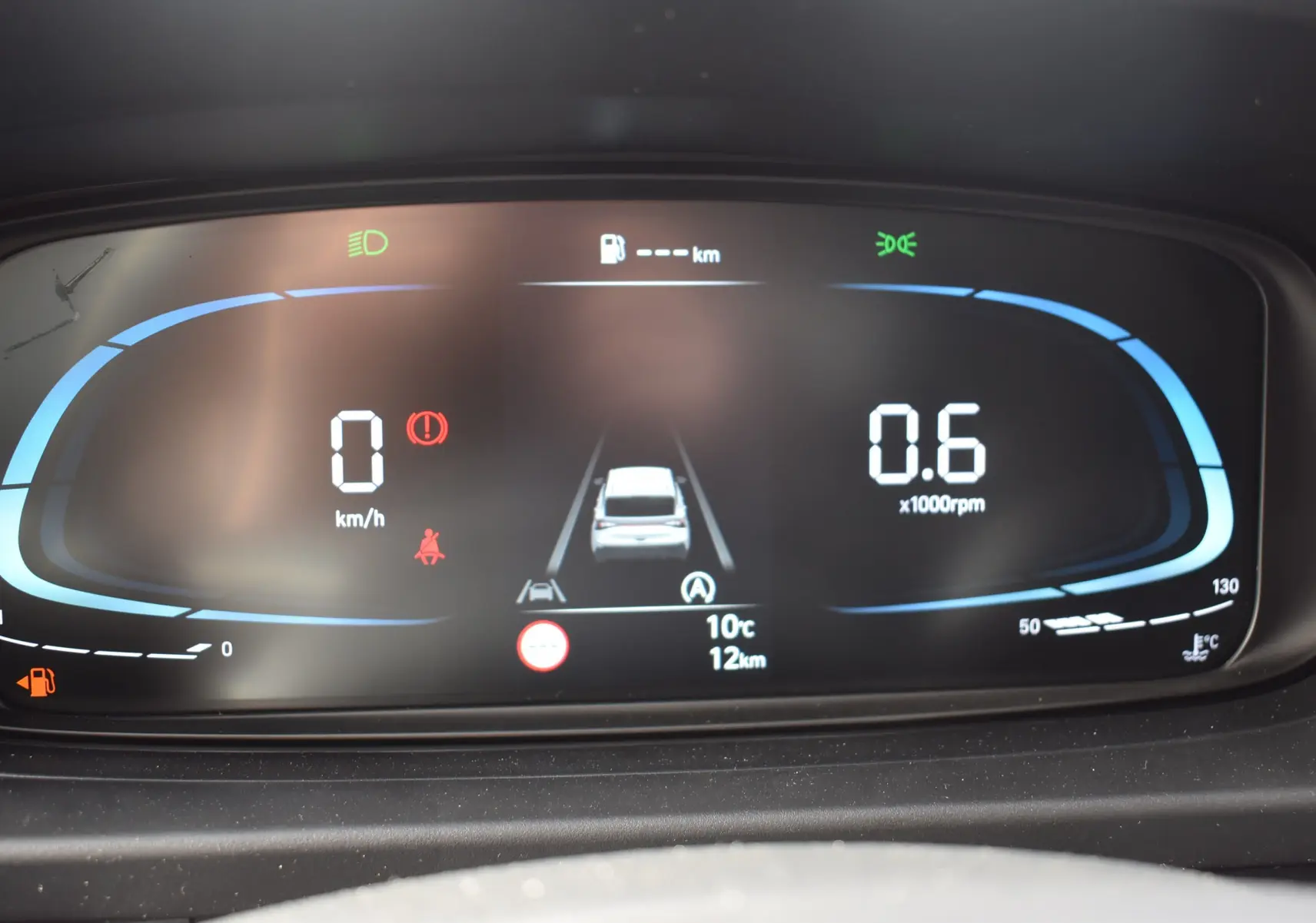 Tableau de bord numérique de la Hyundai i20 2025 affichant vitesse, régime moteur et alertes, avec éclairage bleu et noir.