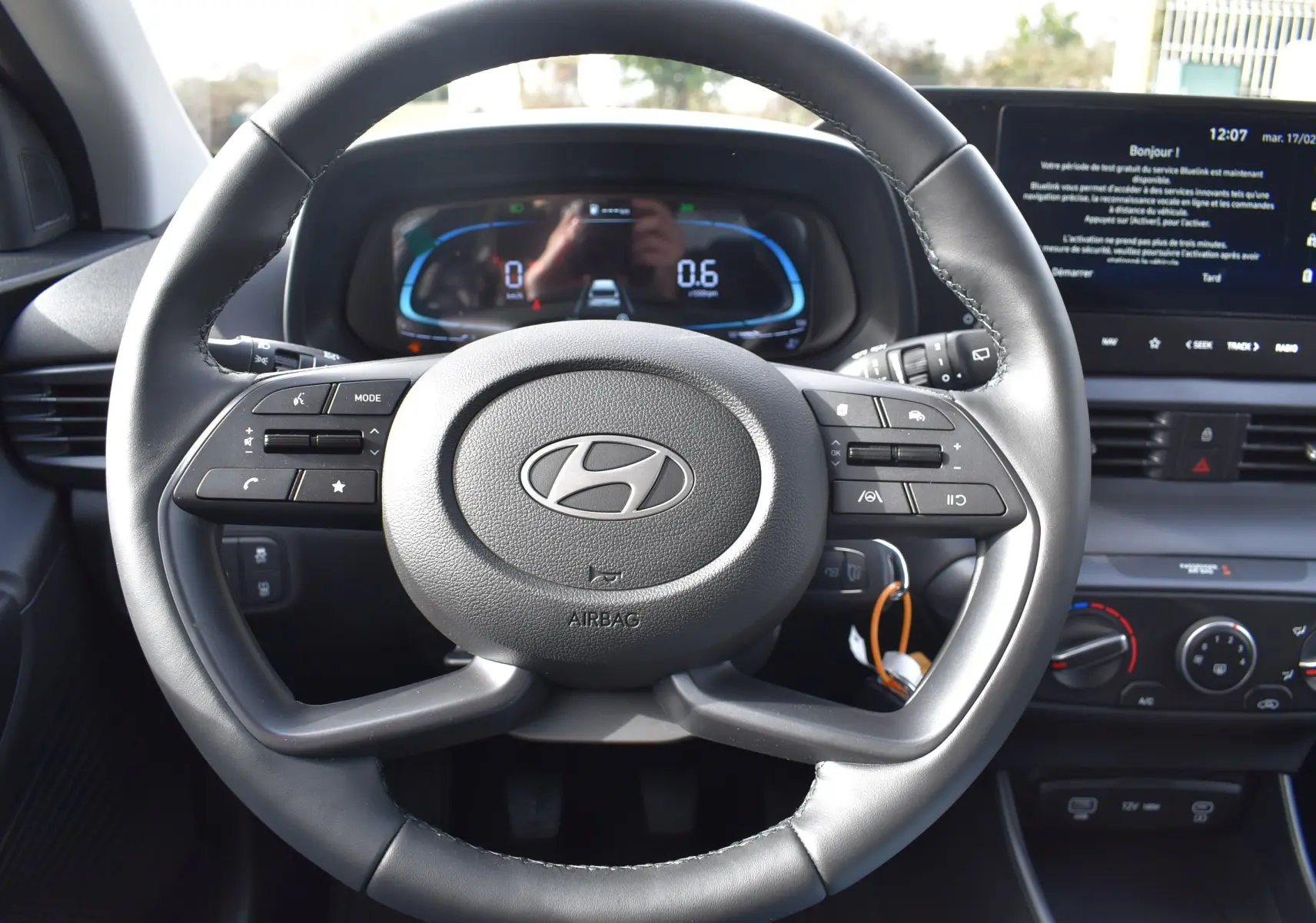 Vue rapprochée du volant en cuir noir de la Hyundai i20 2025 avec commandes multifonctions et tableau de bord digital.