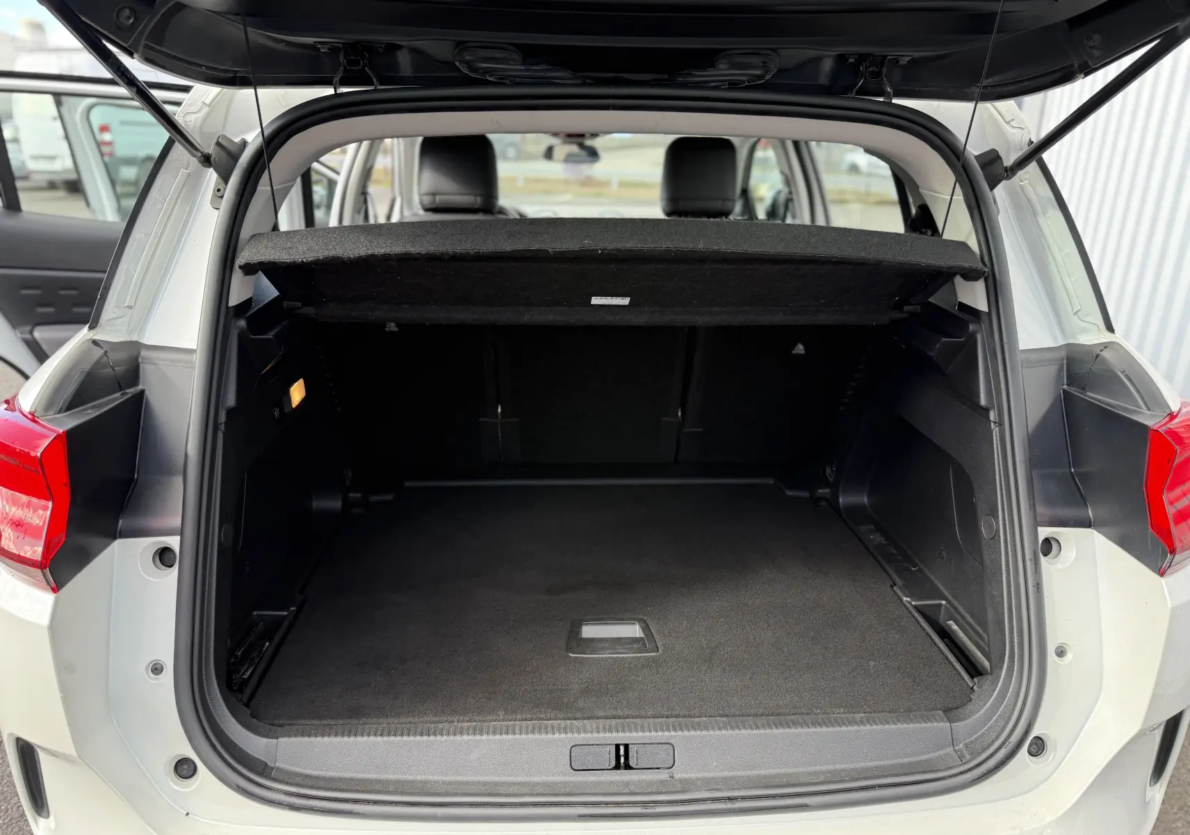 Coffre ouvert vu de l'arrière d'un Citroën C5 Aircross blanc, montrant un espace de chargement vide et propre.