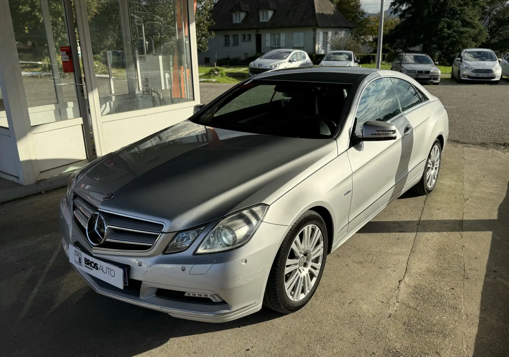Mercedes Classe E 250 Coupé gris vue 3/4 avant droit, avec jantes alliage et toit ouvrant panoramique.