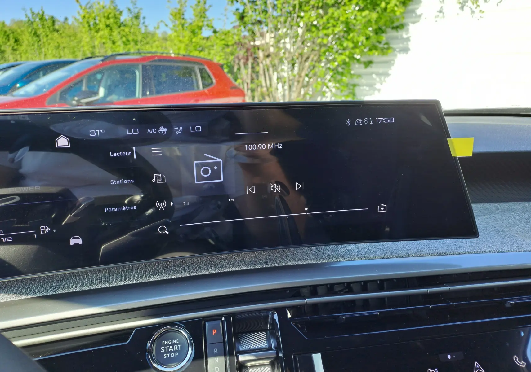 Écran tactile central du tableau de bord du Peugeot 3008 gris Artense, affichant la radio FM à 100.90 MHz en extérieur lumineux.