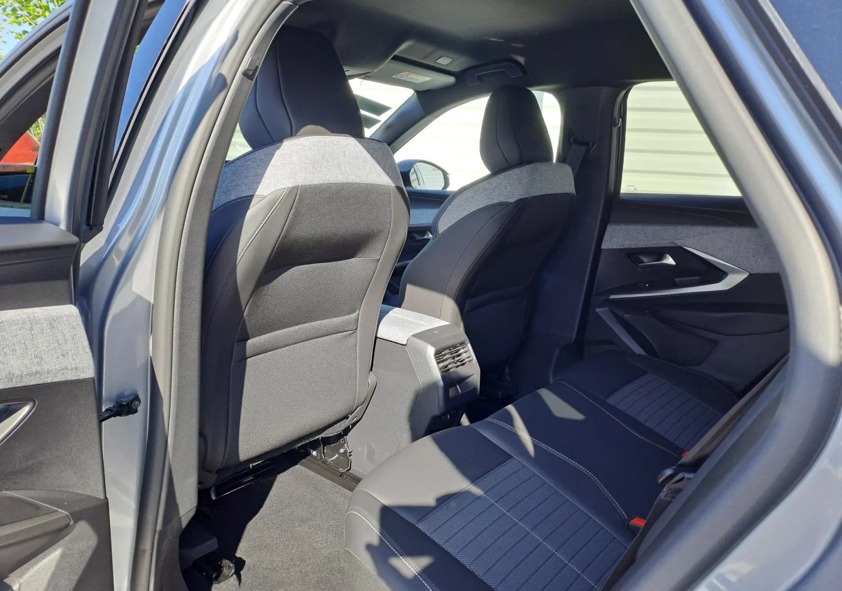 Vue intérieure arrière côté gauche du Peugeot 3008 gris Artense, mettant en valeur les sièges tissu et cuir bicolores.