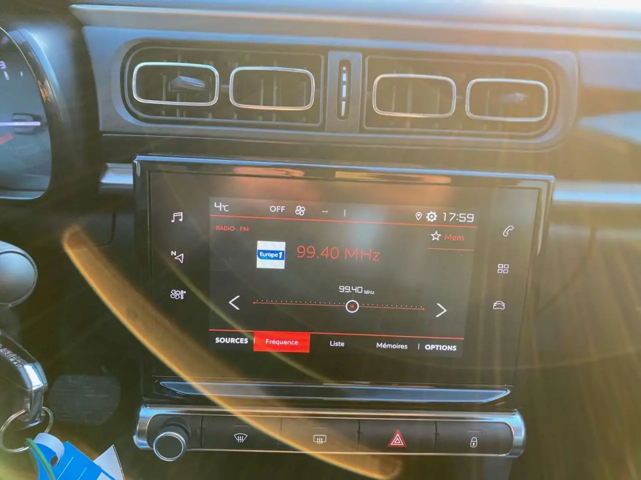 Écran tactile multimédia allumé sur la radio, tableau de bord intérieur de Citroën C3 Shine 2023, ambiance sombre.