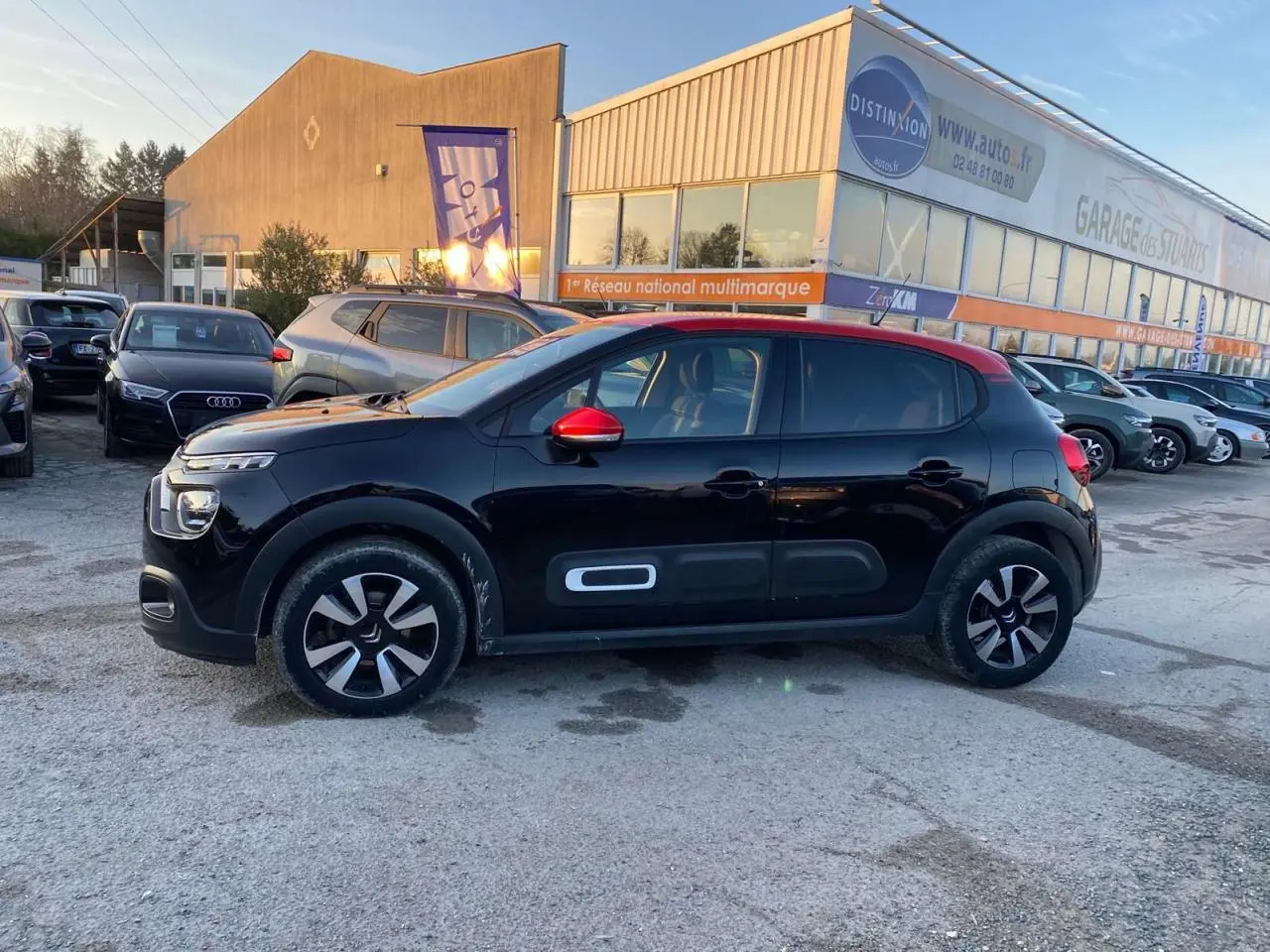 Profil côté gauche d'une Citroën C3 Shine 2023 noire avec toit rouge et jantes alliage diamantées.