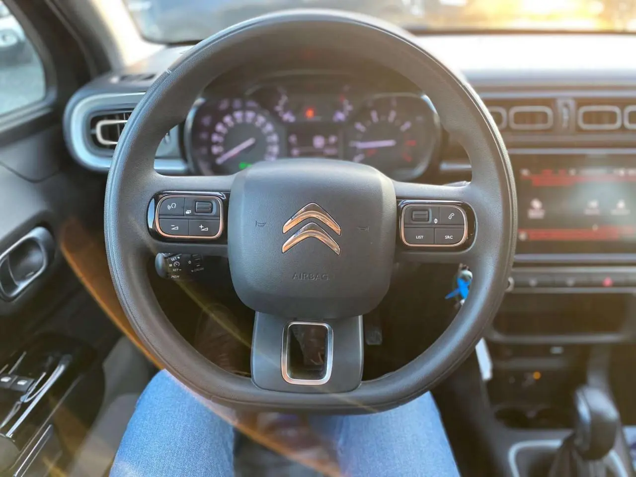 Vue centrée sur le volant noir de la Citroën C3 Shine 2023, avec tableau de bord et commandes visibles en arrière-plan.