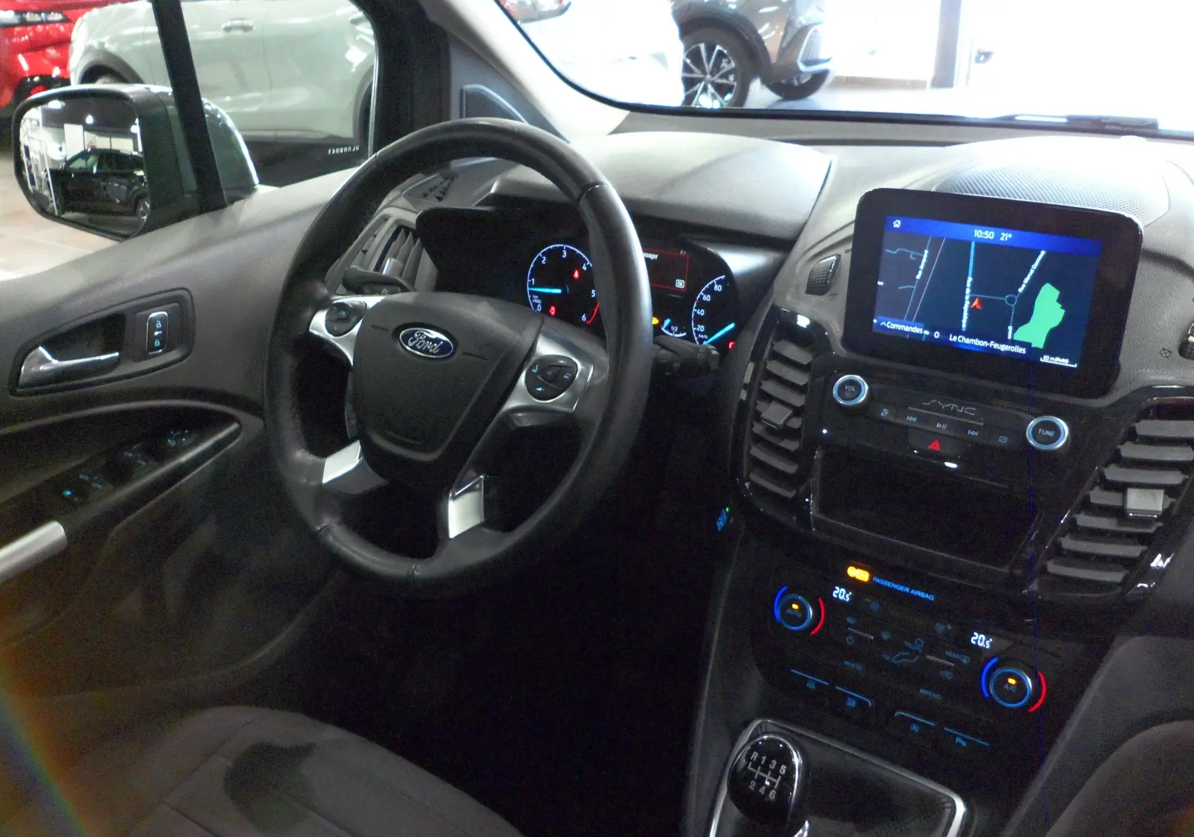 Intérieur du Ford Grand Tourneo Connect gris, vue côté conducteur sur volant, tableau de bord et écran tactile GPS.