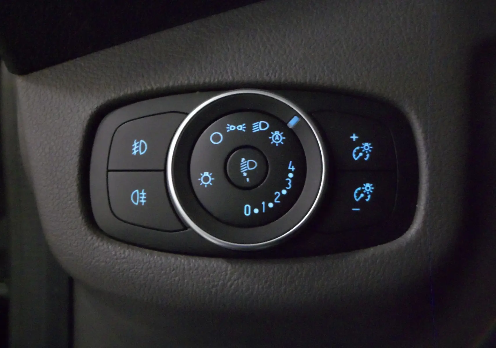 Gros plan sur le bouton de réglage des phares avec éclairage bleu dans l'habitacle gris du Ford Grand Tourneo Connect 2020.