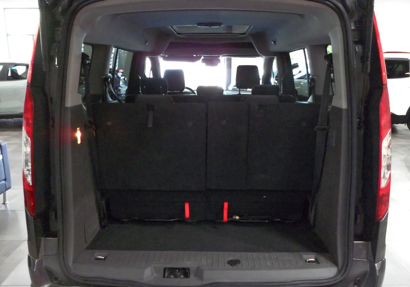 Vue arrière du Ford Grand Tourneo Connect gris Magnetic 2020 avec coffre ouvert et sièges rabattus visibles.