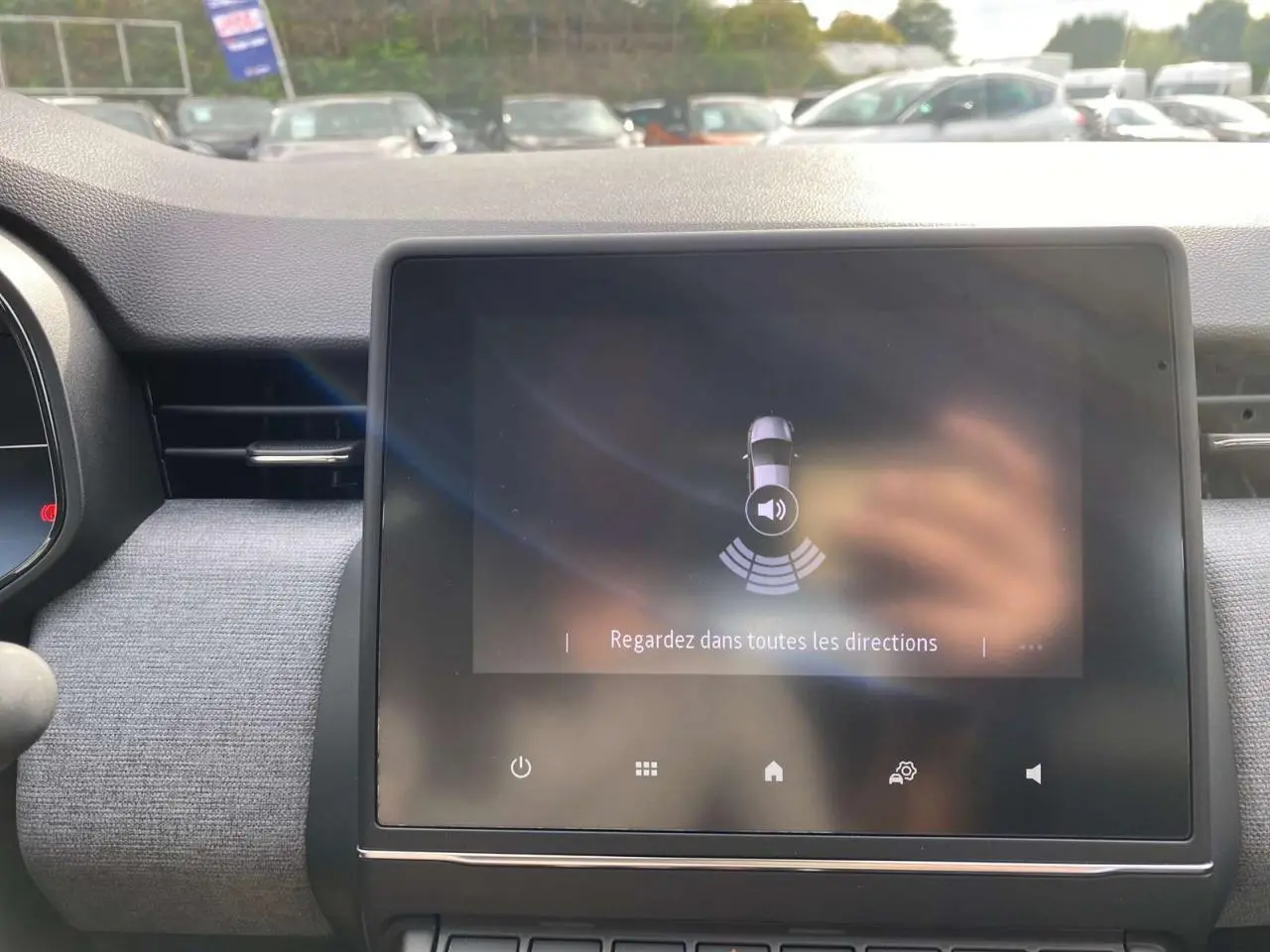 Écran tactile central de la Renault Clio 2025 affichant l'aide au stationnement arrière dans un intérieur gris.