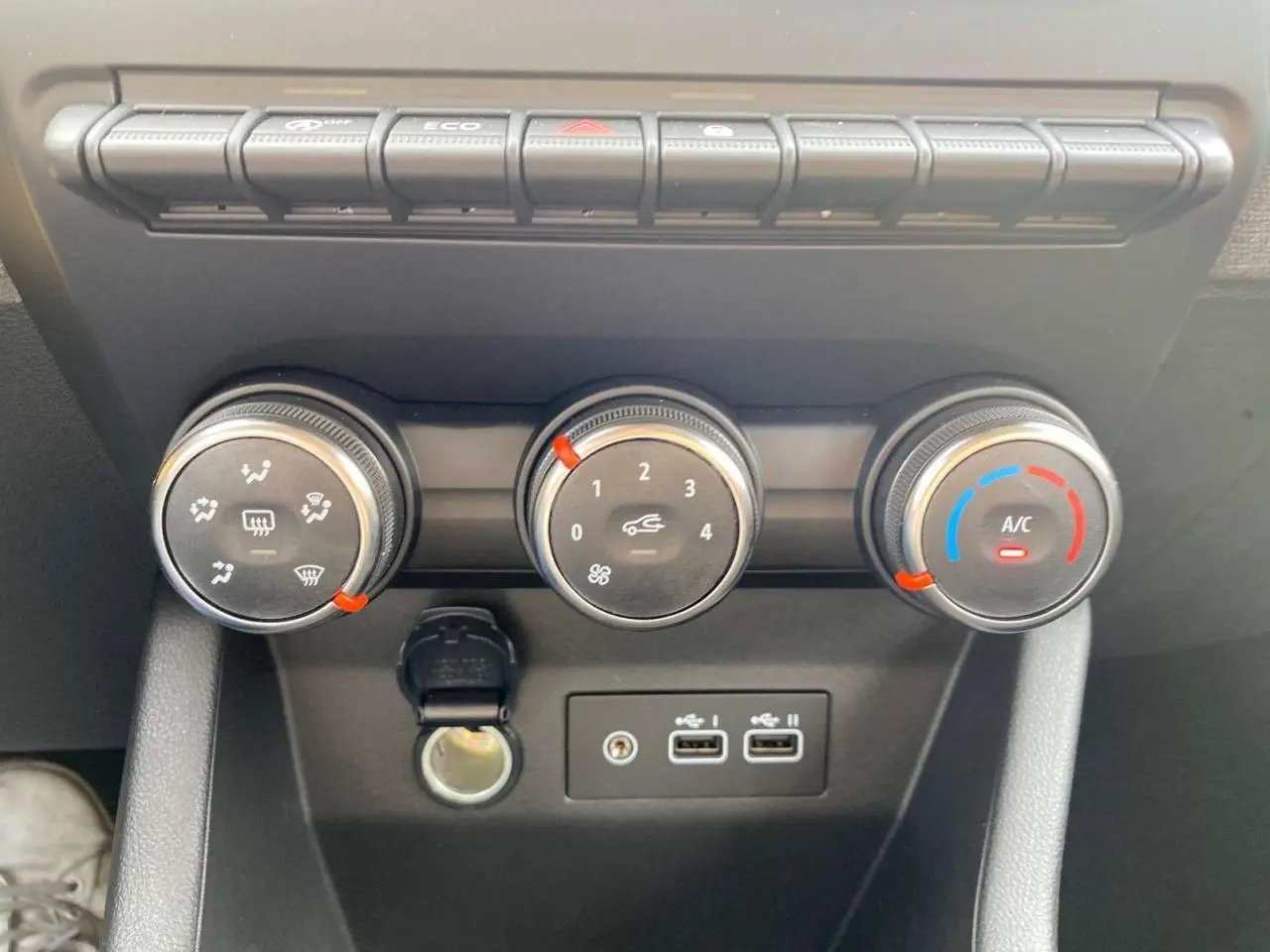 Gros plan sur les commandes de climatisation manuelle et les ports USB de la Renault Clio Evolution 2025 en noir étoilé.