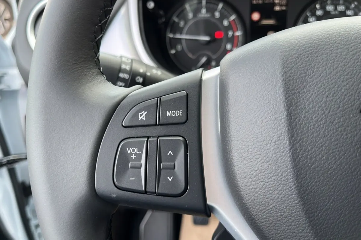 Gros plan sur les commandes audio au volant du Suzuki Vitara 2025 White Pearl, version hybride essence automatique.