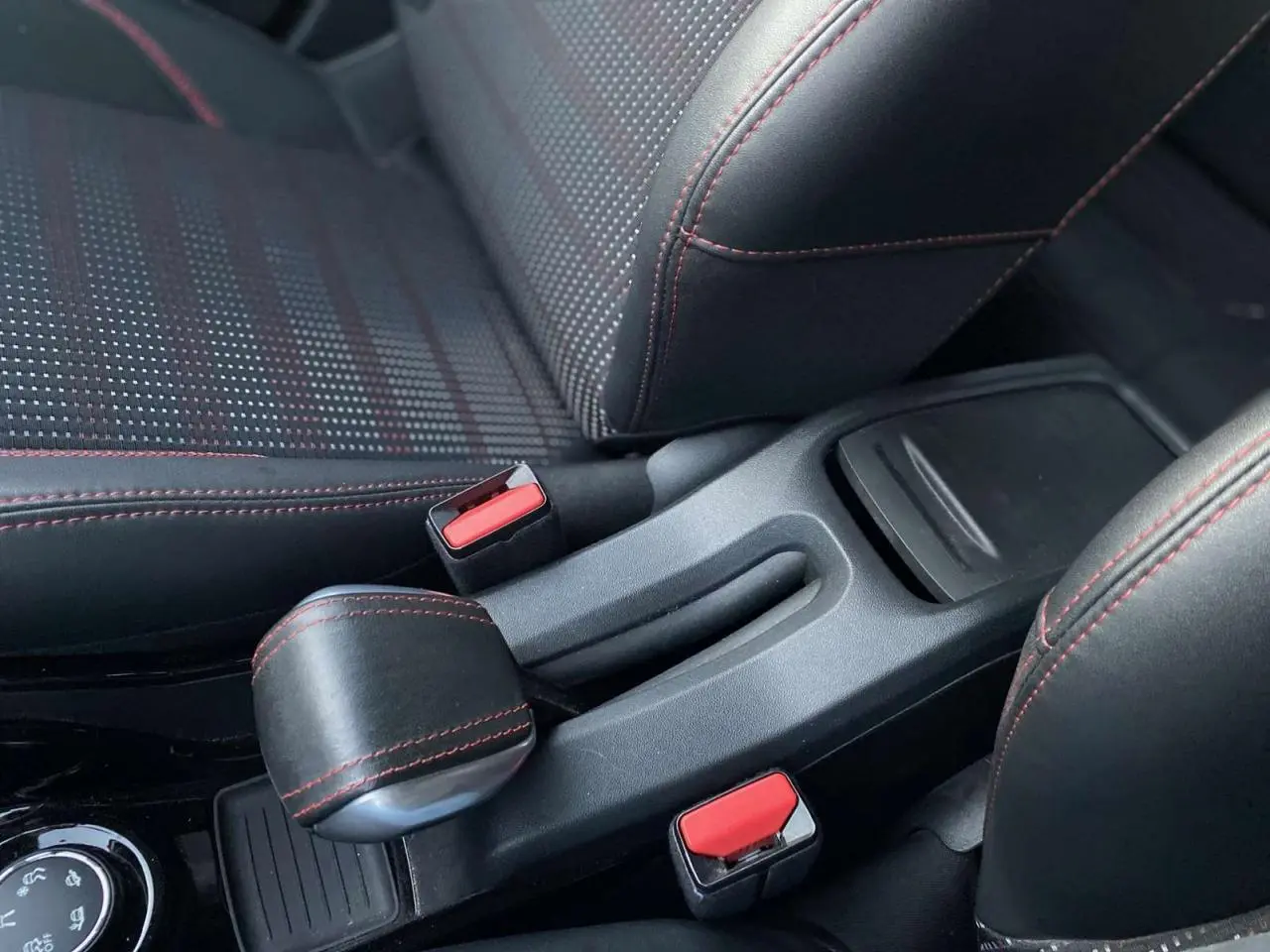 Gros plan sur la console centrale et les sièges noirs avec surpiqûres rouges du Peugeot 2008 GT Line blanc de 2016.