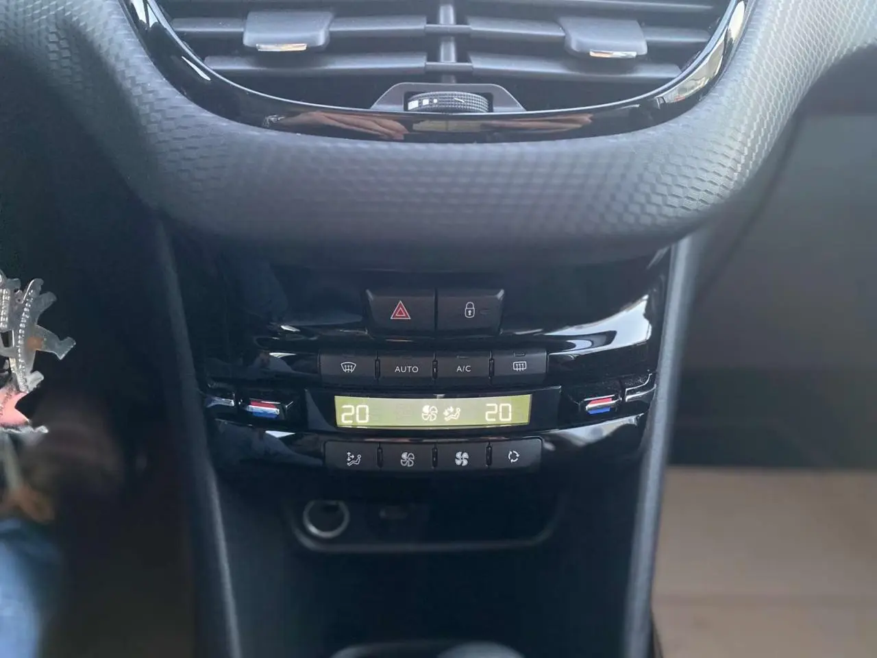 Vue rapprochée de la console centrale noire du Peugeot 2008 blanc GT Line, affichant la climatisation à 20 degrés.