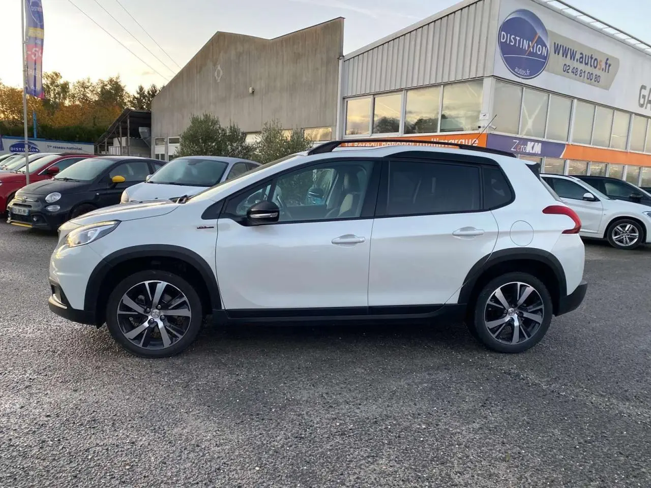 Profil côté gauche d'un Peugeot 2008 blanc GT Line 2016 avec jantes alliage et toit noir sur parking extérieur.