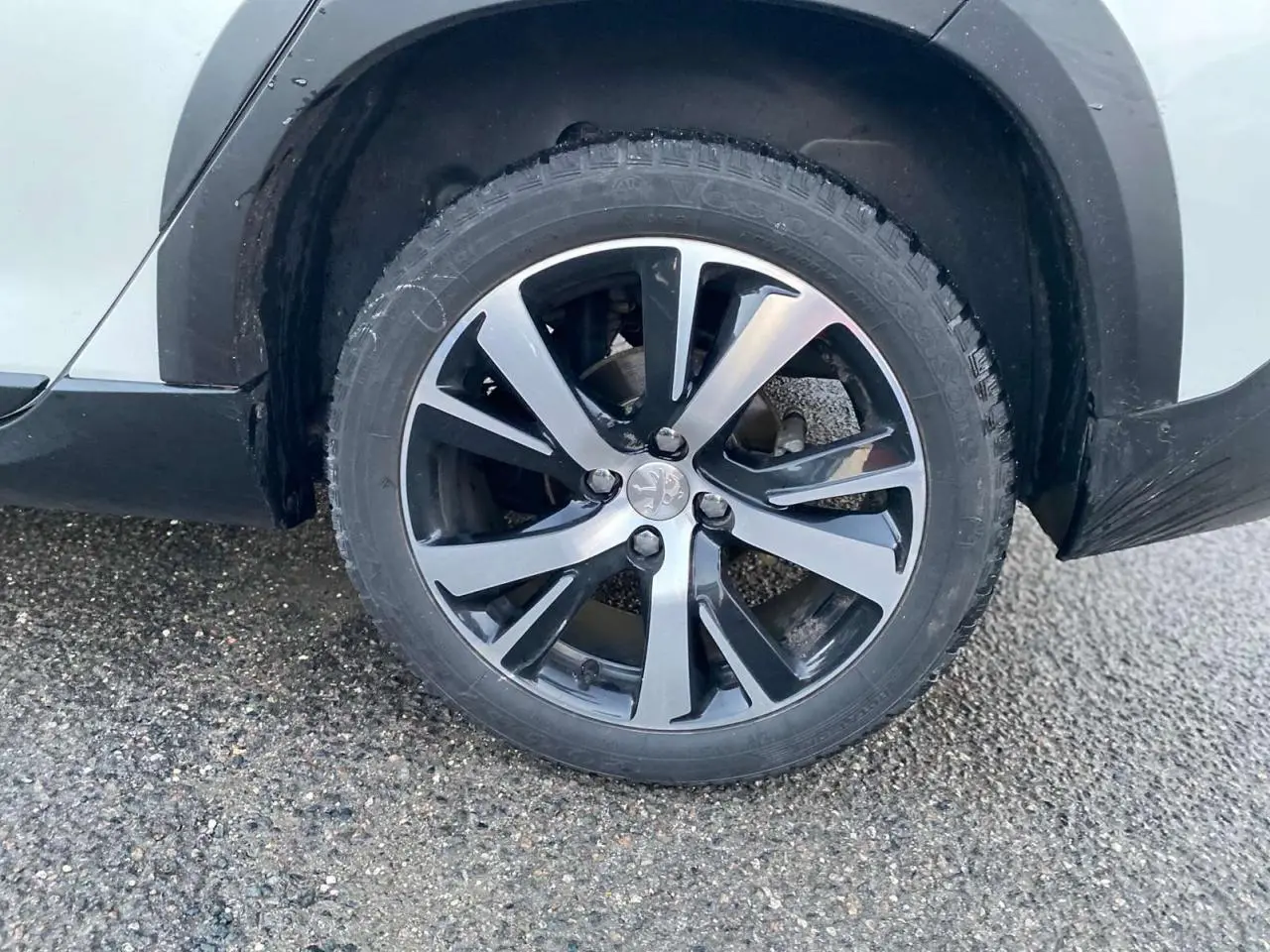 Gros plan sur la roue avant droite d'un Peugeot 2008 blanc 2016 avec jante alliage bicolore GT Line.