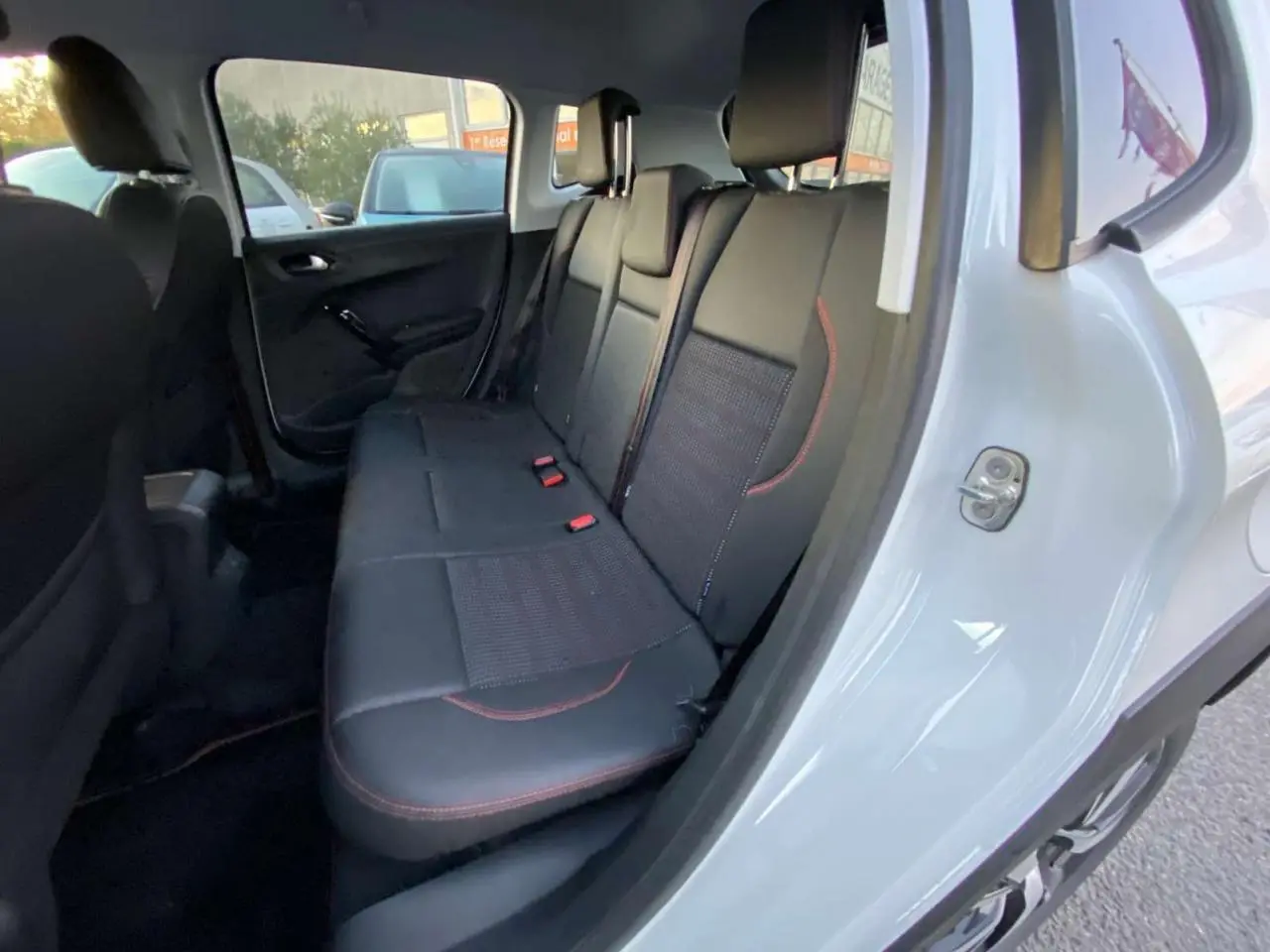 Intérieur arrière du Peugeot 2008 blanc 2016, vue côté droit sur les sièges noirs avec surpiqûres rouges.