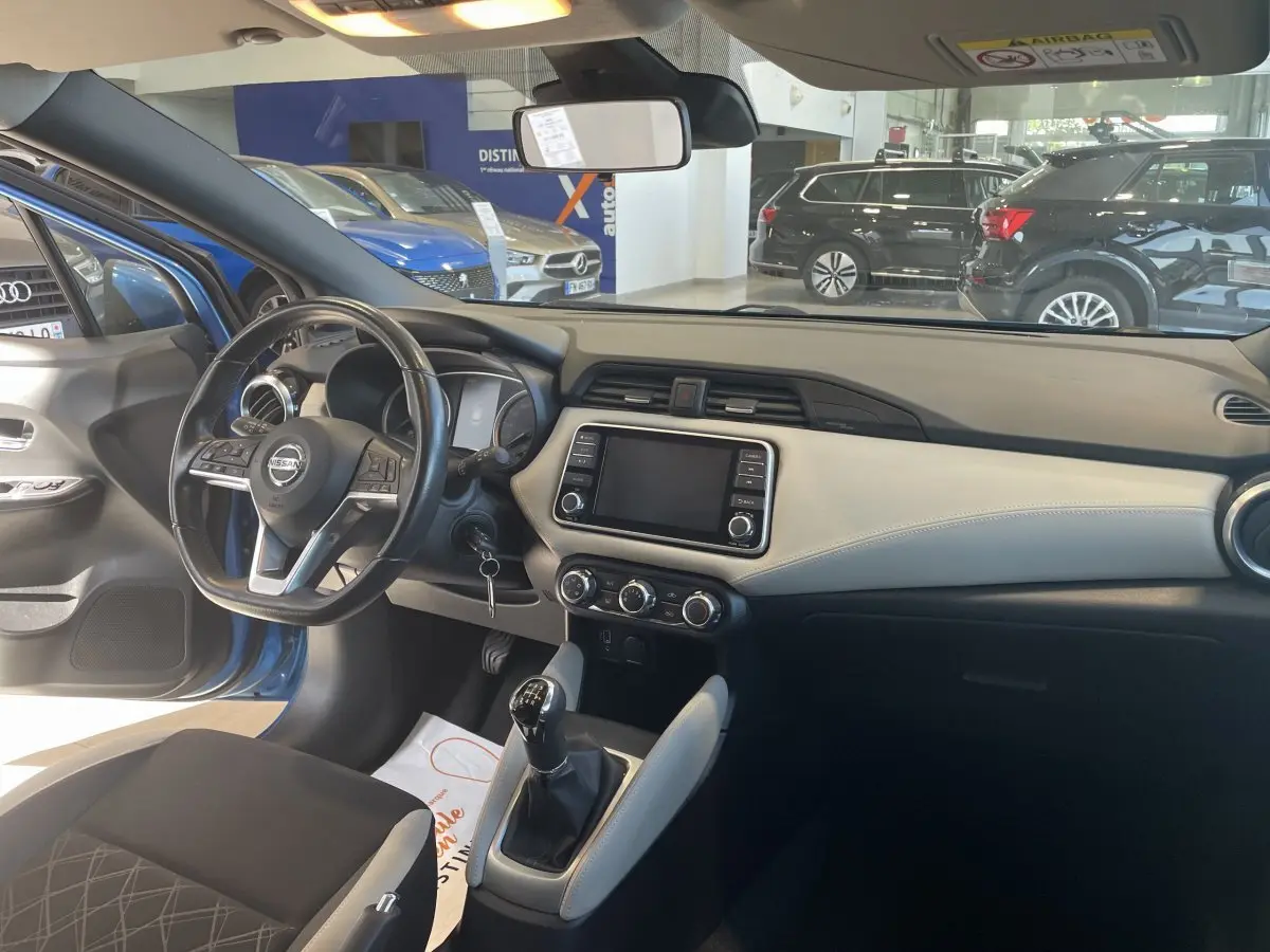 Intérieur avant droit d'une Nissan Micra bleu 2020, volant cuir multifonctions et écran tactile central visible.
