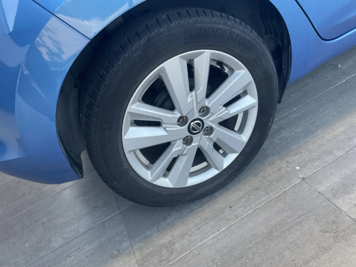 Gros plan sur la roue avant gauche d'une Nissan Micra bleu 2020, avec jante alliage et pneu Bridgestone.